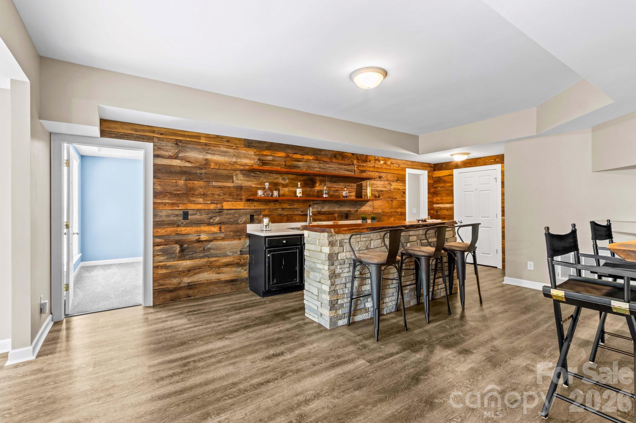Bar area of basement level has wood accent wall, sink, and plenty of space for seating. - 12822 Cadgwith Cove Drive, Huntersville