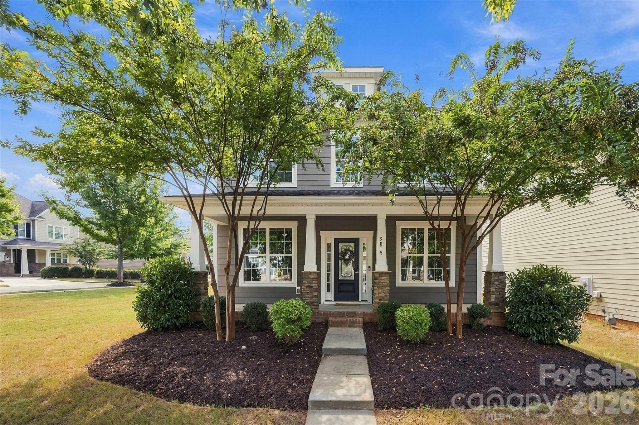 Charming curb appeal with a welcoming covered front porch, mature landscaping, and beautiful architectural details - 2015 Kensley Drive, Waxhaw