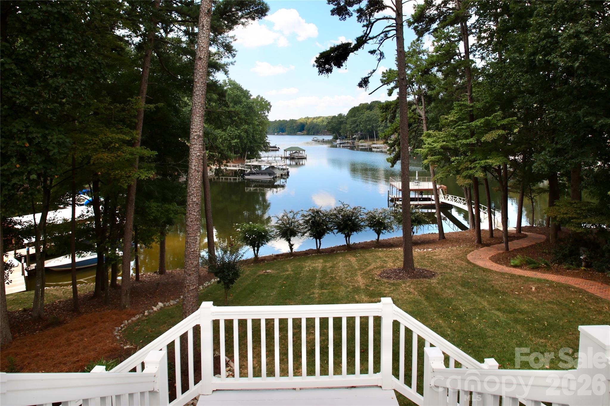 Enjoy lake living from your expansive top deck with dual staircase, to your patio below, to your dock on the water. - 140 Holt Lane, Mooresville