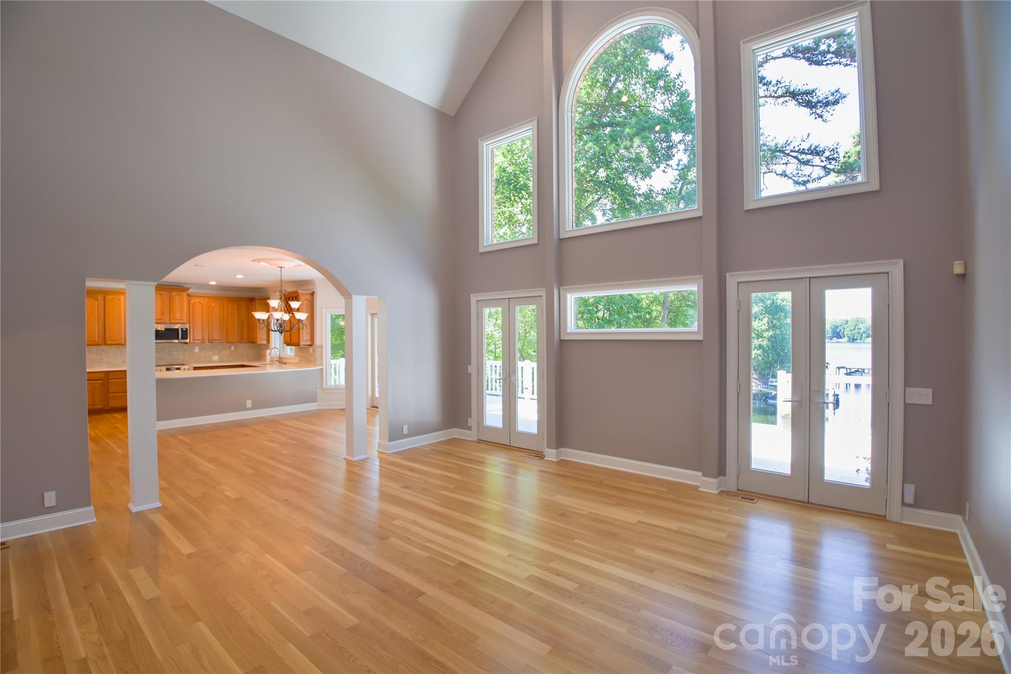 Bright and airy great room with newly refinished hardwood floors flows into dining area and kitchen through stunning arch. - 140 Holt Lane, Mooresville