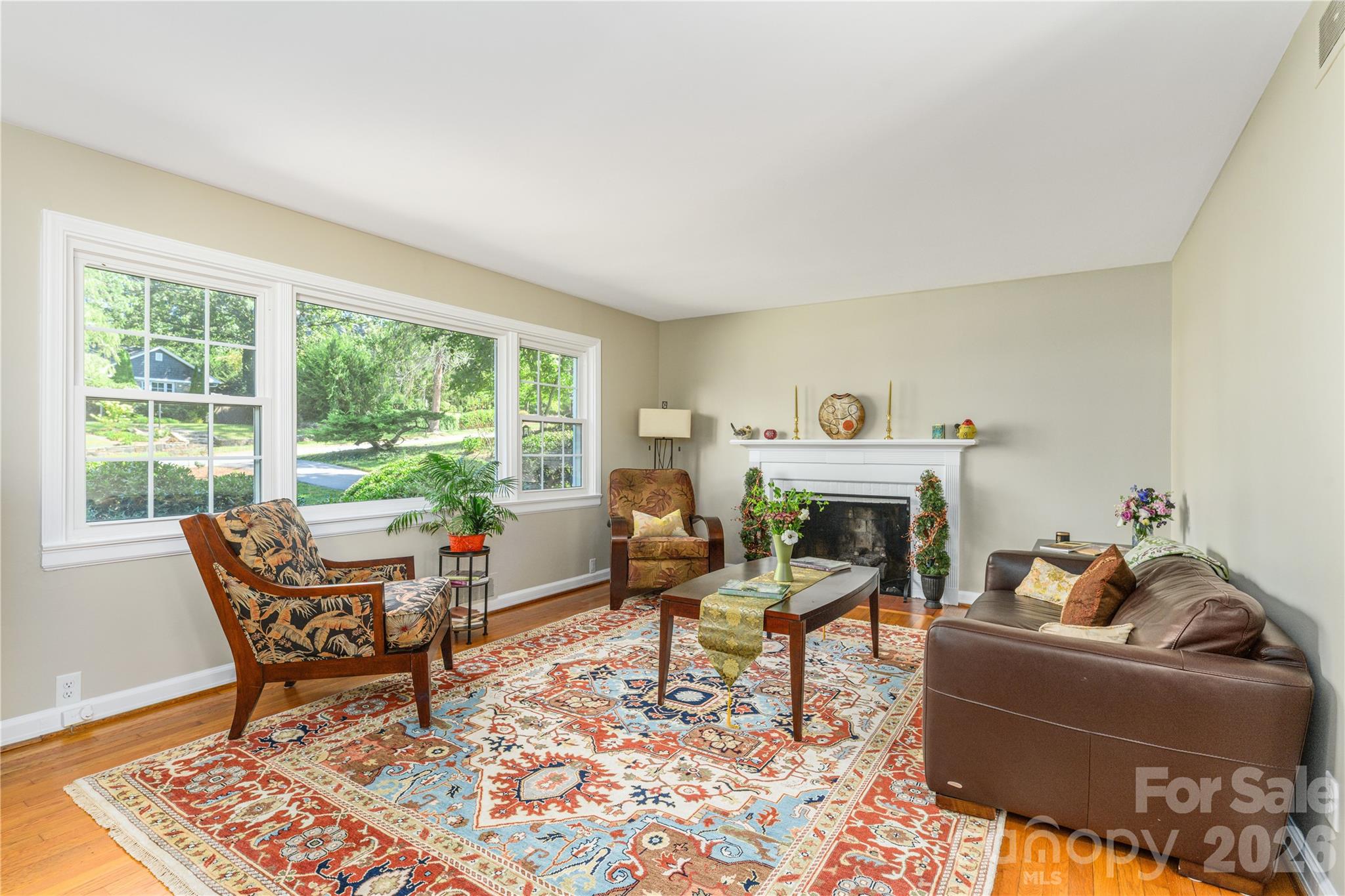 Light-filled living room featuring expansive windows and a cozy gas log fireplace. - 111 Gracelyn Road, Asheville