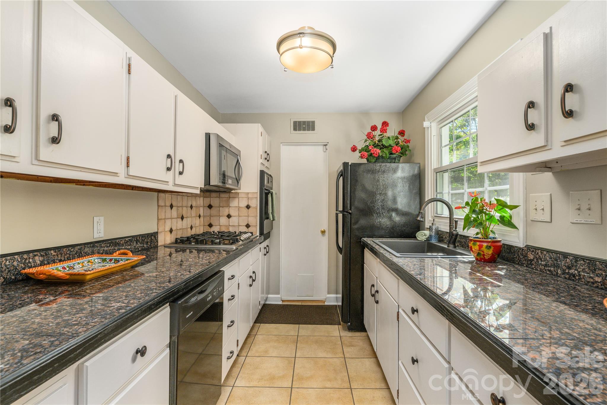 Kitchen with tile floor and granite countertops also offers an abundance of storage. Door leads to attached single car garage. - 111 Gracelyn Road, Asheville