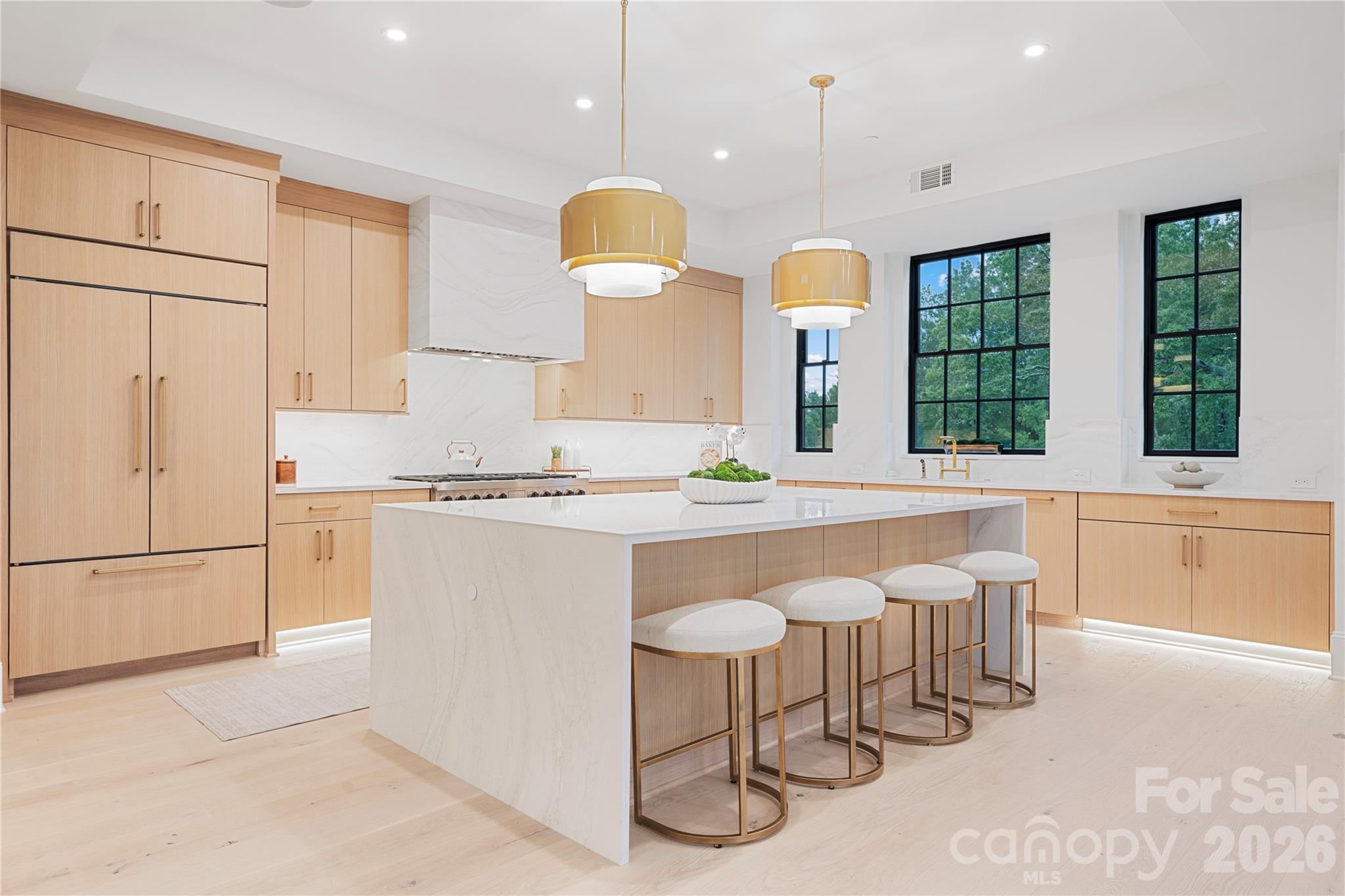 The beautifully designed gourmet kitchen with a extra-wide waterfall-edge island, custom light-wood cabinetry, dramatic stone surfaces and abundant natural light. - 409 Queens Road, Charlotte