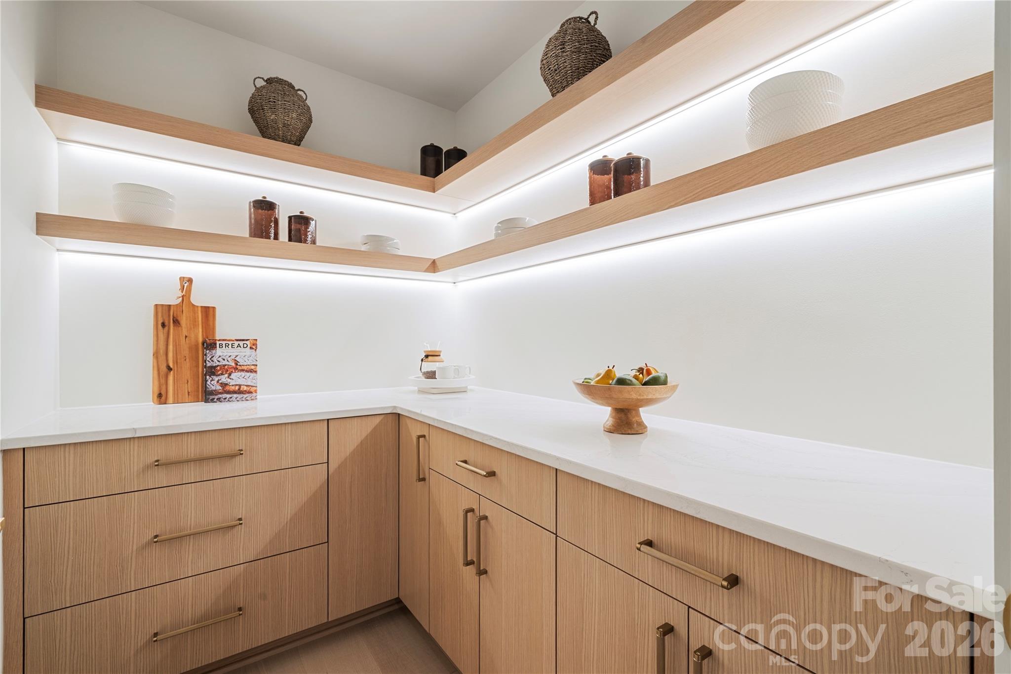 The spacious walk-in pantry provides generous counter space, extensive cabinetry and illuminated open shelving for beautifully organized storage. - 409 Queens Road, Charlotte