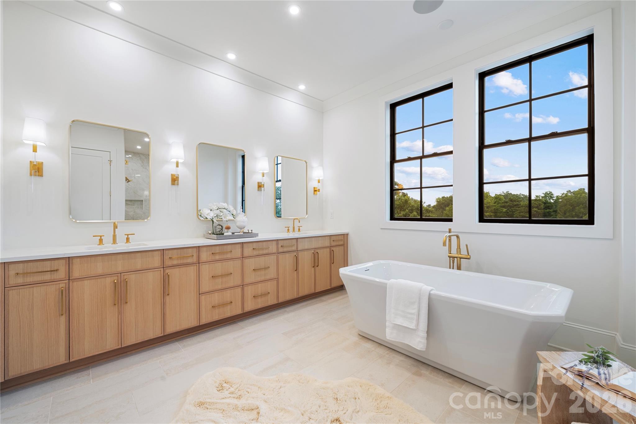 The expansive custom vanity with dual sinks, triplet mirrors and abundant cabinetry ties the room together and fulfills every need for this extraordinary primary bathroom. - 409 Queens Road, Charlotte