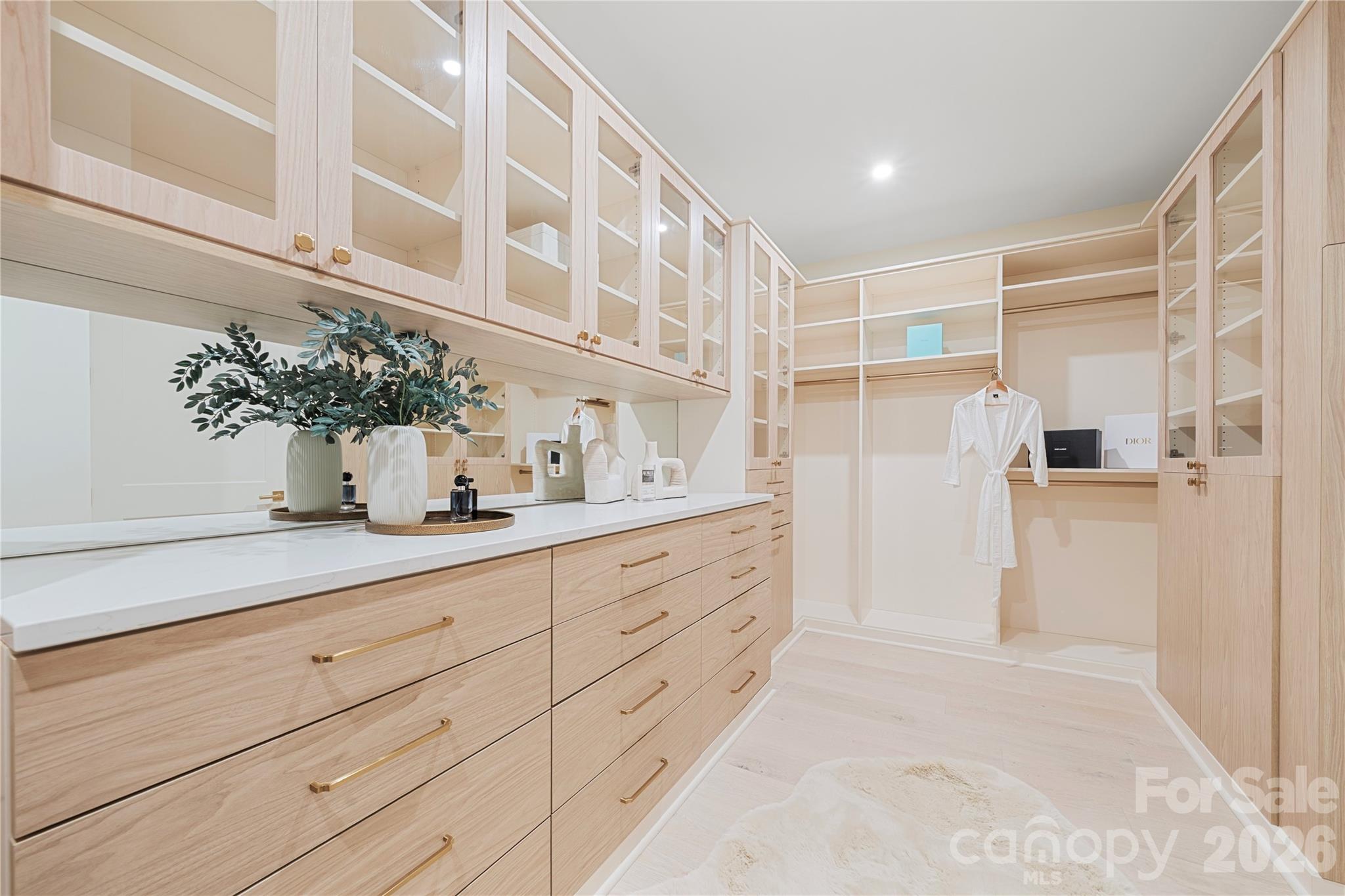 The beautifully finished primary dressing room provides extensive custom cabinetry, glass-front storage, generous drawers and abundant hanging racks for your every need. - 409 Queens Road, Charlotte