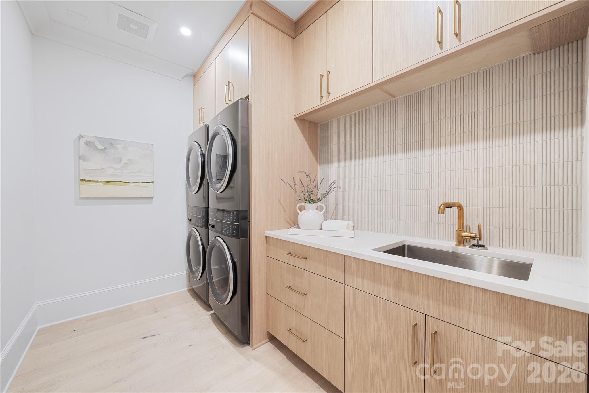 The well-appointed laundry room provides a double washer, and a double dryer setup! This unique private laundry provides extensive custom cabinetry for storage, a double wide stainless steel utility sink and generous counter space for everyday convenience. - 409 Queens Road, Charlotte