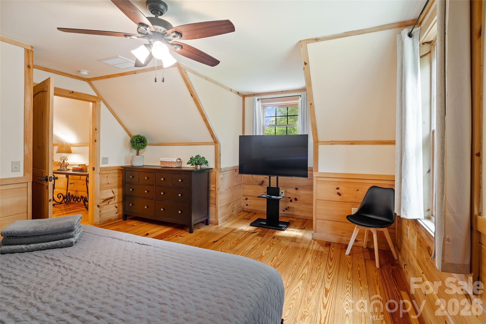 Opposite view of the upstairs bedroom showcasing character-rich pine trim, plenty of floor space for dressers and media setups, and soft natural light throughout. - 213 Big Valley Road, Pisgah Forest