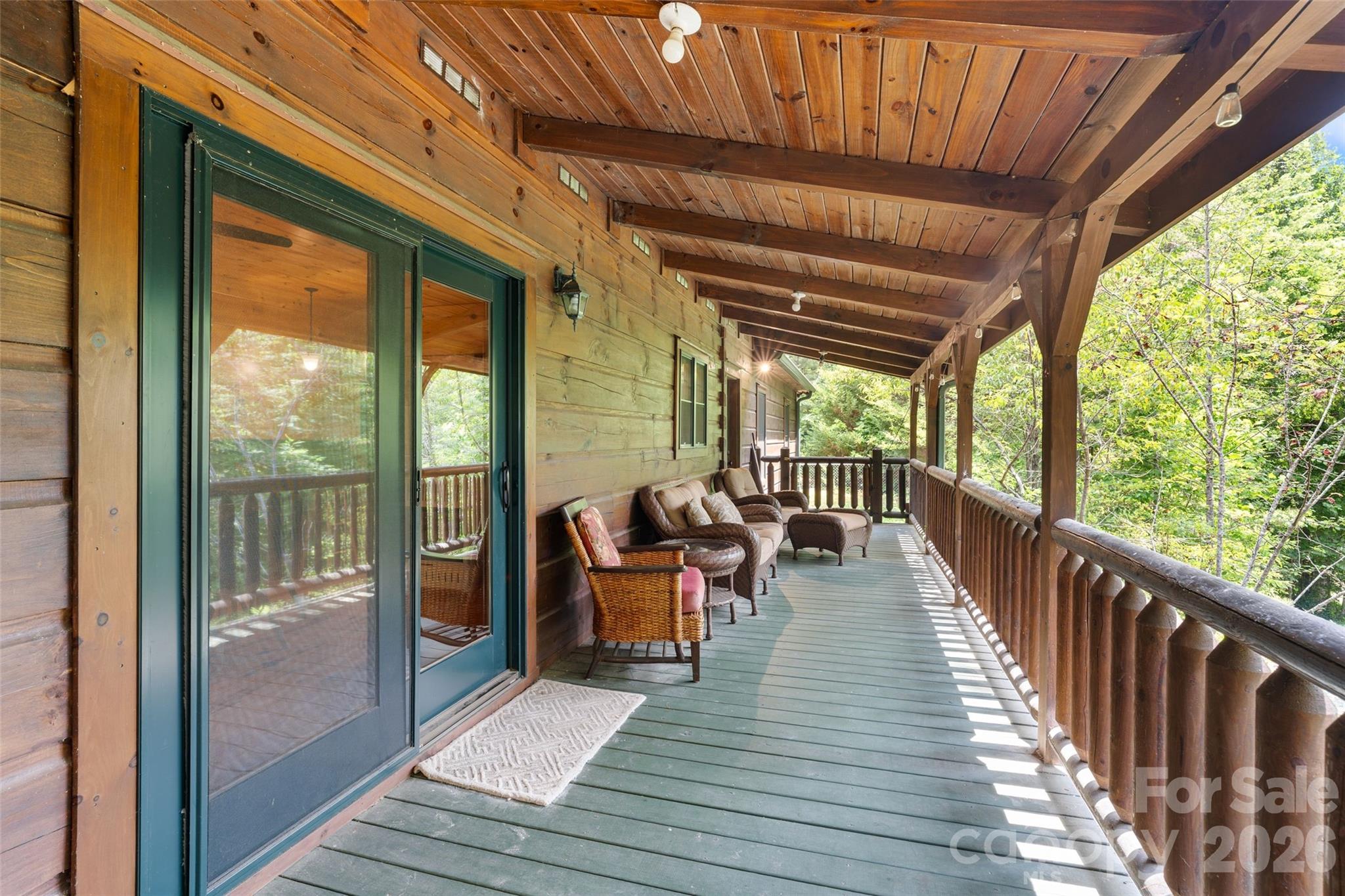 Expansive outdoor living space with rustic log railings and exposed beams. - 213 Big Valley Road, Pisgah Forest