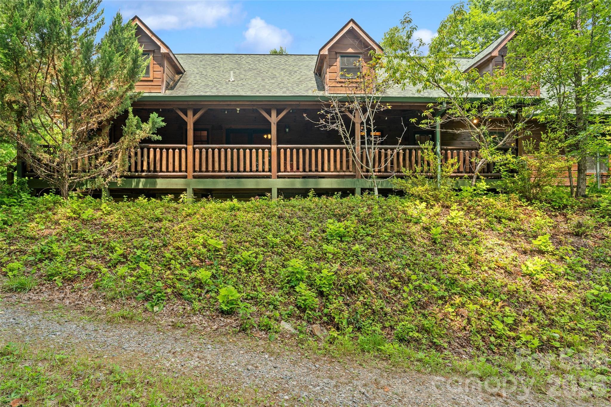 Elevated front facade showcasing the massive covered porch. - 213 Big Valley Road, Pisgah Forest