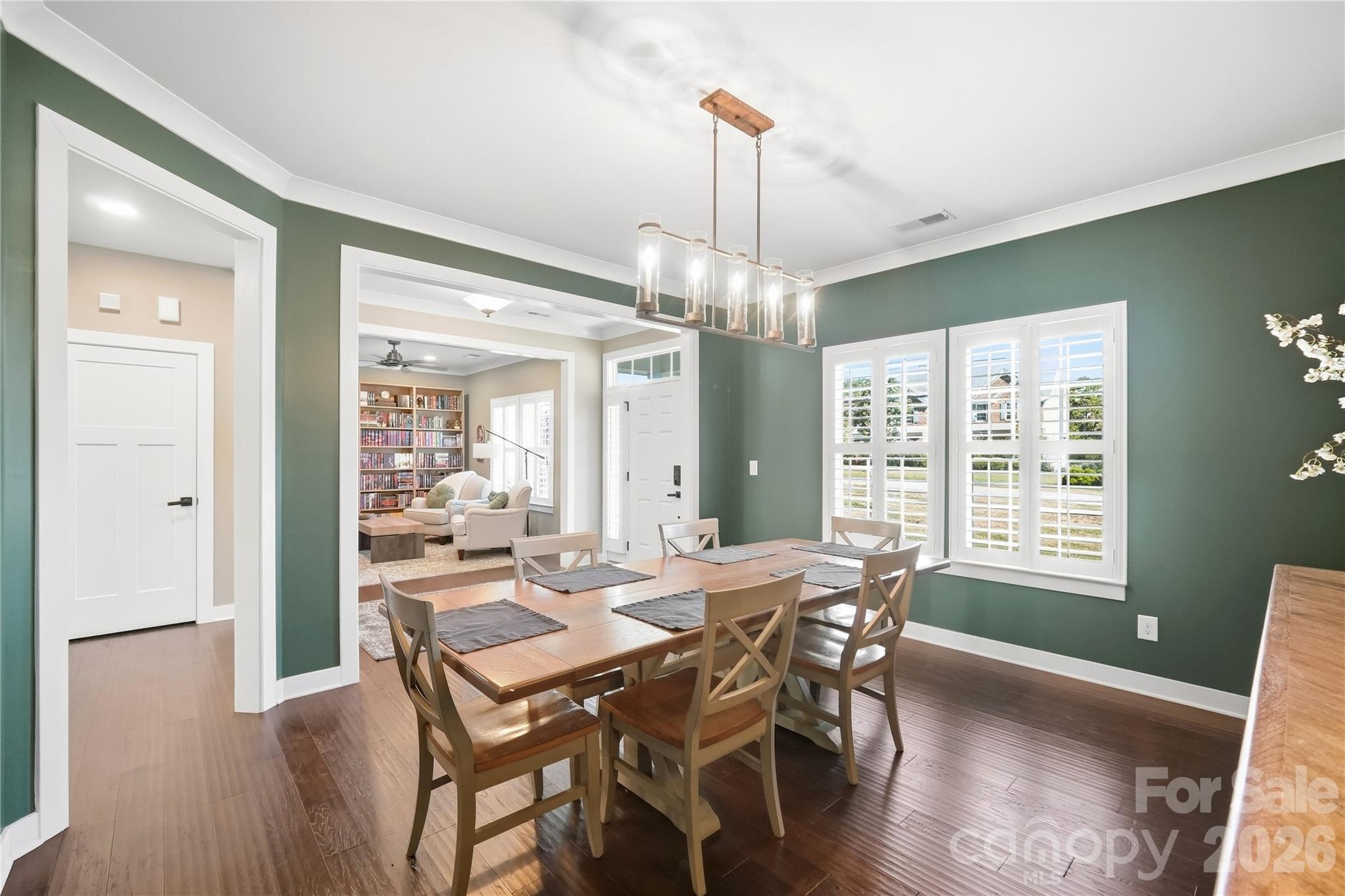 Formal dining room with plantation shutters, crown molding, and wide cased openings to the foyer and den. - 912 Manorwood Drive, Waxhaw