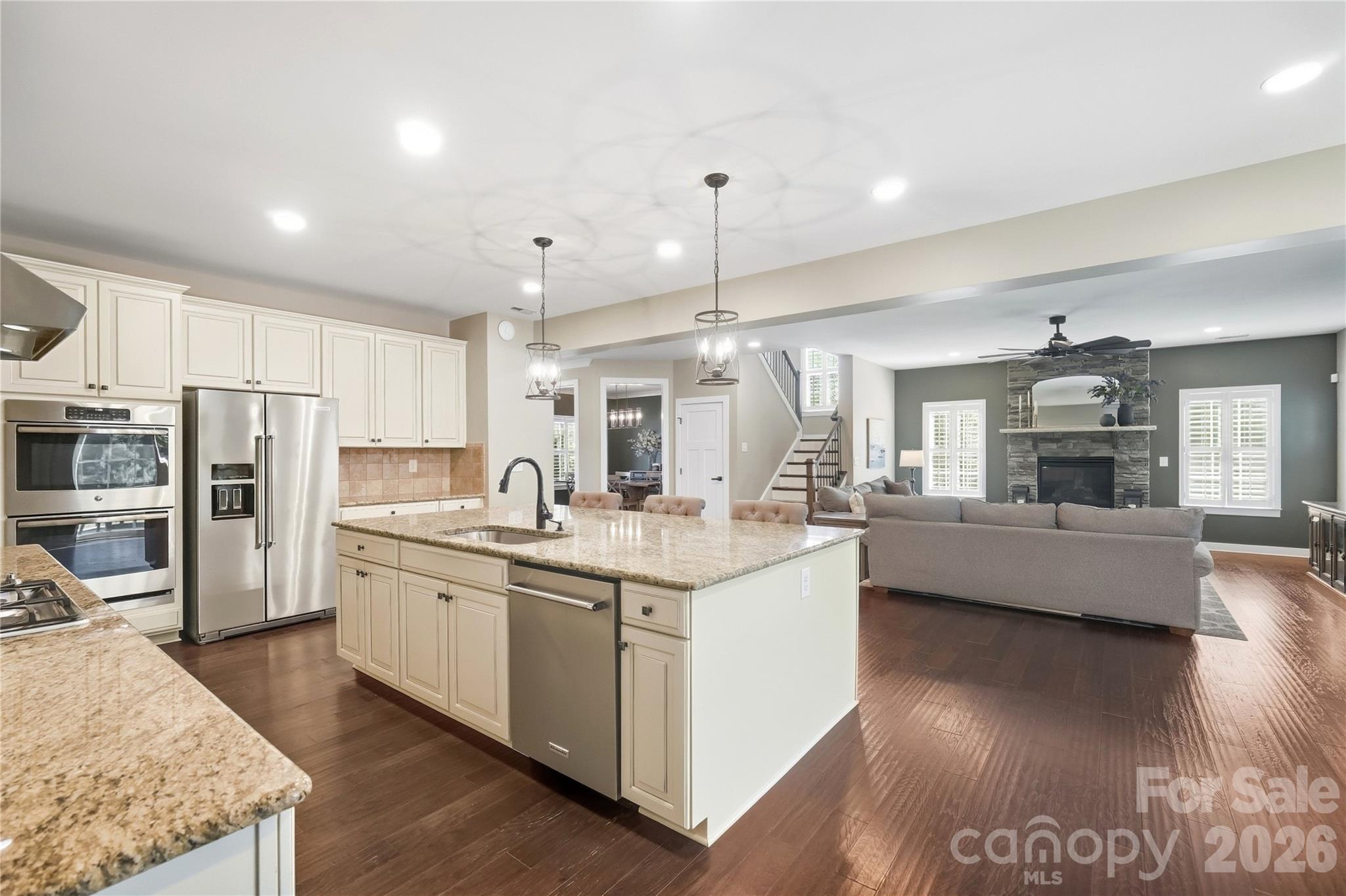 Open layout from the kitchen to the family room, with a stone-surround fireplace, plantation shutters, and hardwood floors throughout. - 912 Manorwood Drive, Waxhaw