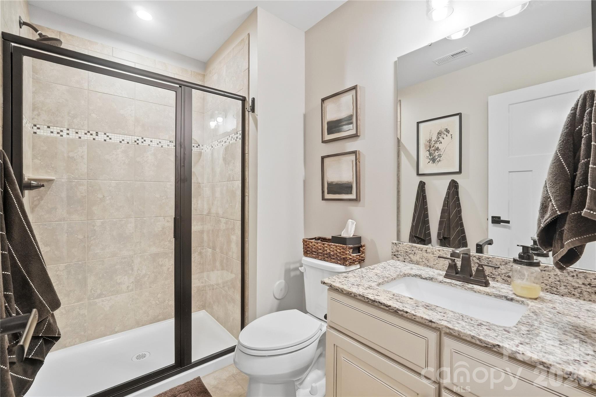 Main-level full bath with a walk-in tile shower and granite vanity, steps from the study. - 912 Manorwood Drive, Waxhaw