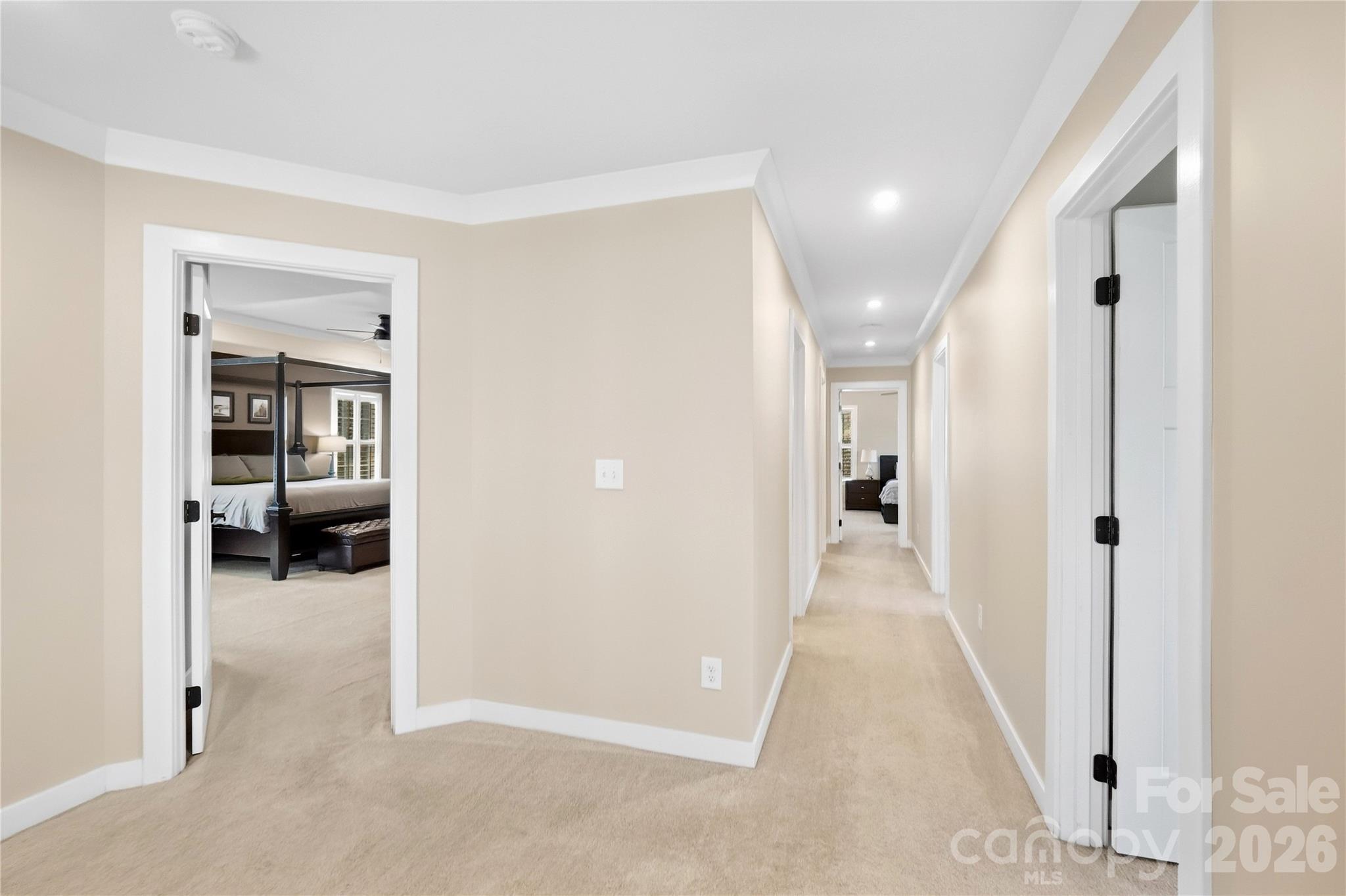Upper hallway with crown molding and recessed lighting, leading to the primary suite and secondary bedrooms. - 912 Manorwood Drive, Waxhaw