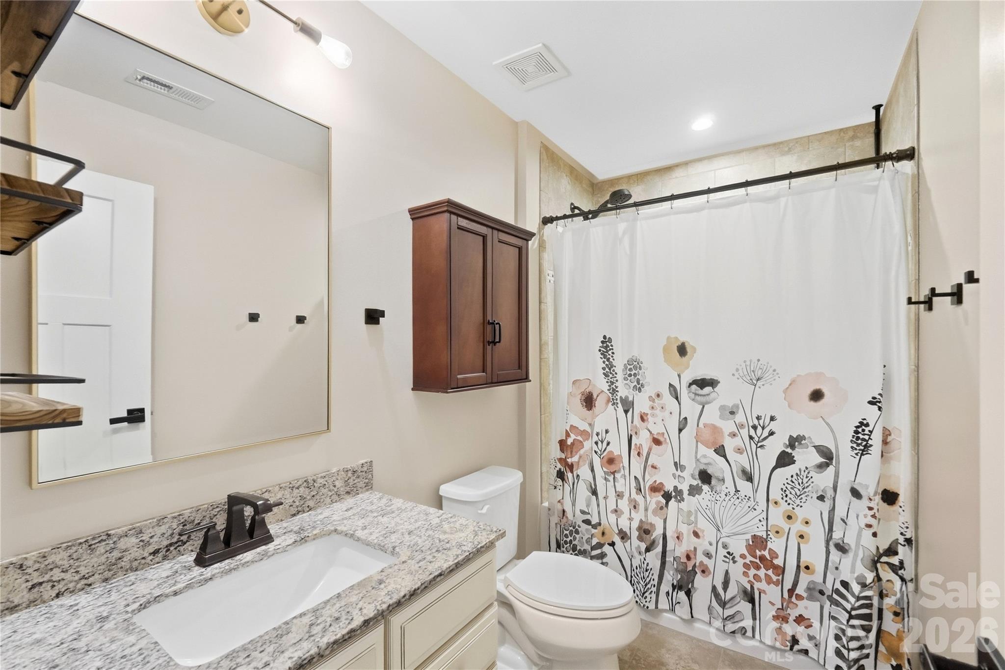 Bedroom 2's private full bath, with a granite vanity and a tub/shower combination with a tile surround. - 912 Manorwood Drive, Waxhaw