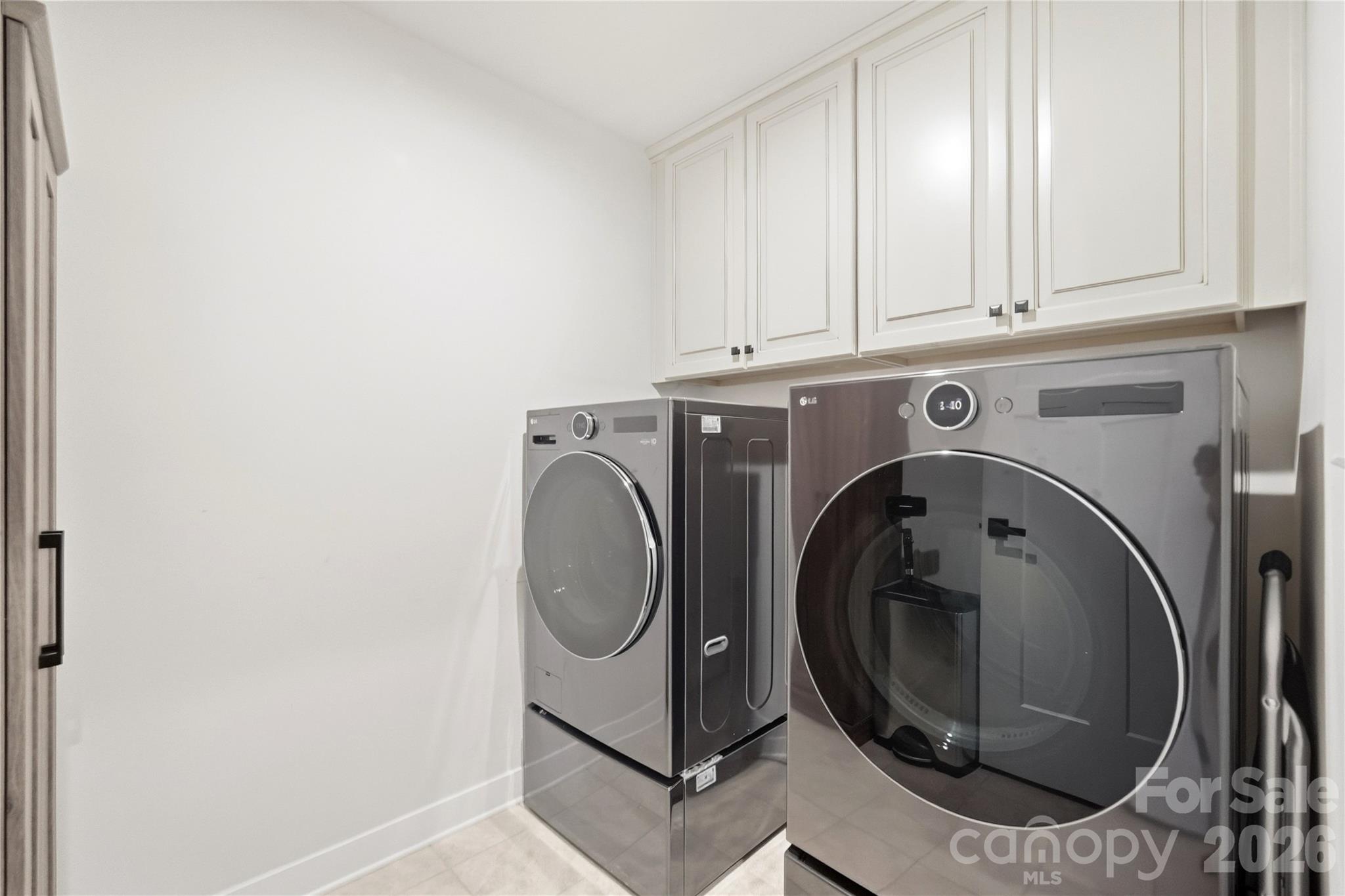 Upper-level laundry room with overhead cabinetry for storage, conveniently located near the bedrooms. - 912 Manorwood Drive, Waxhaw