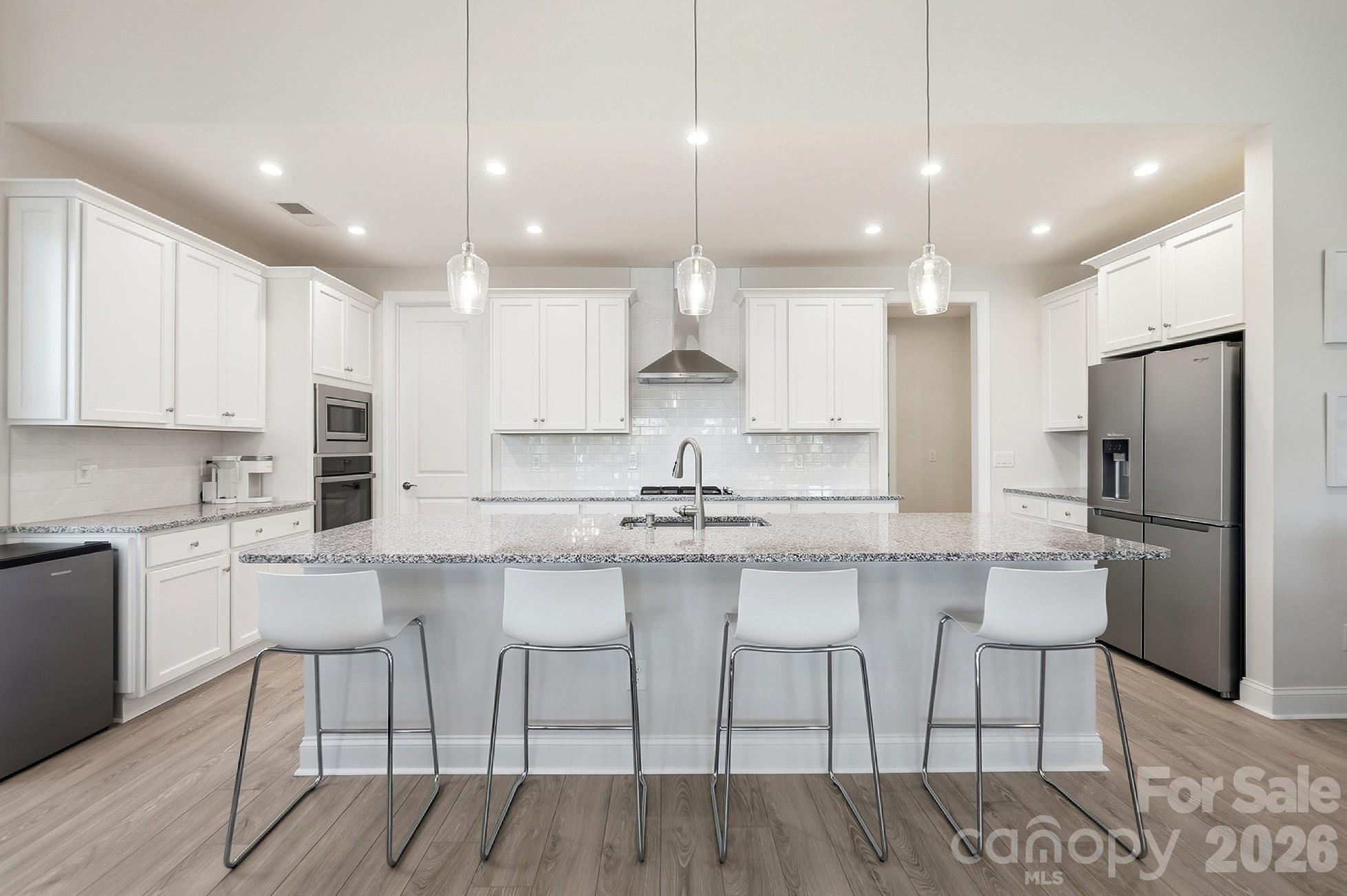 The well-appointed kitchen features ss  appliances, gas cooktop, wall oven, a large center island with abundant seating, and a spacious walk-in pantry, all opening to the dining area and great room - 8032 Longwaters Court, York