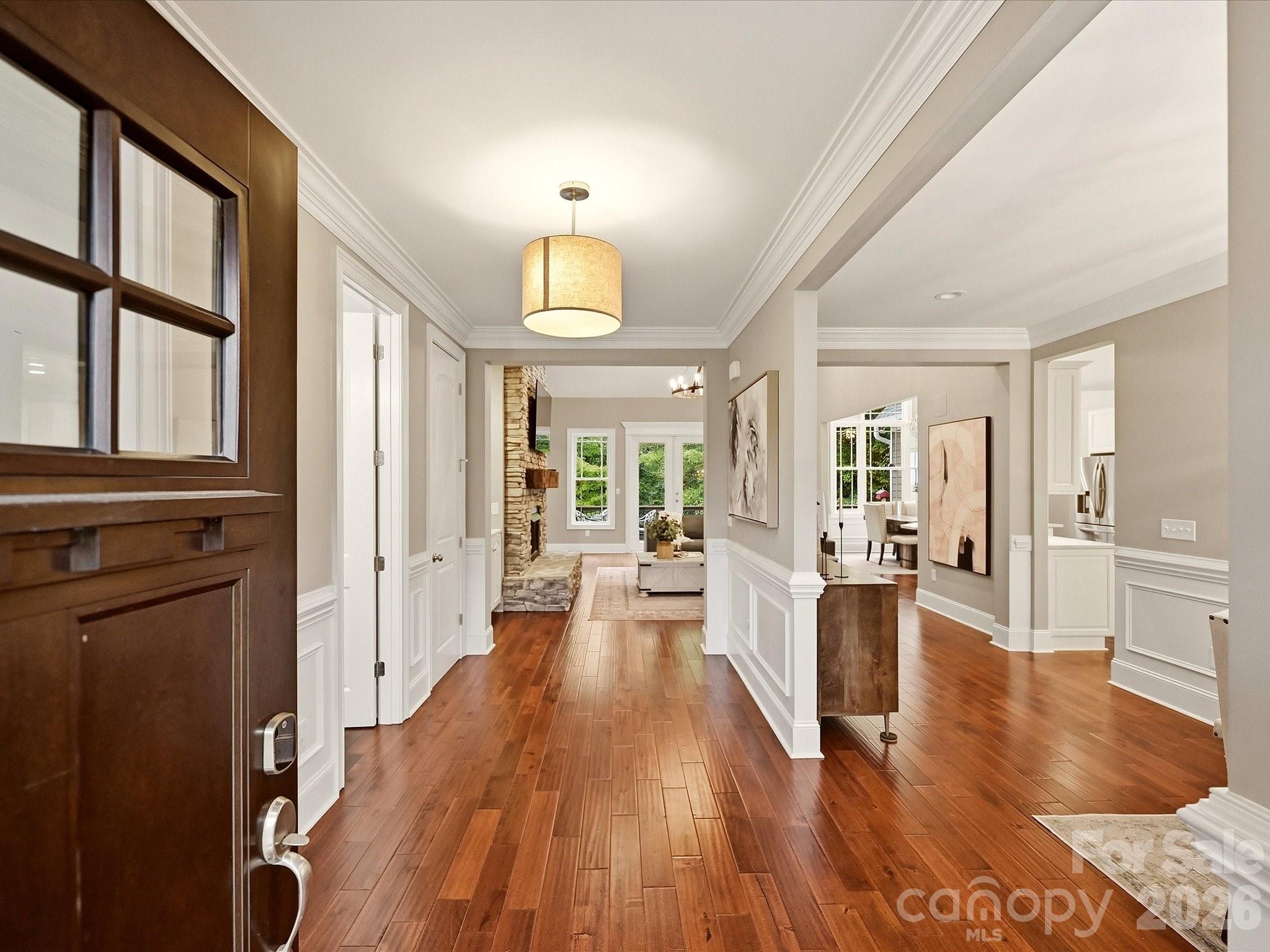 A welcoming entrance features rich floors, elegant crown molding and wainscoting, creating a warm first impression with an open view into the home’s main living spaces. - 3167 James Plantation Drive, Denver