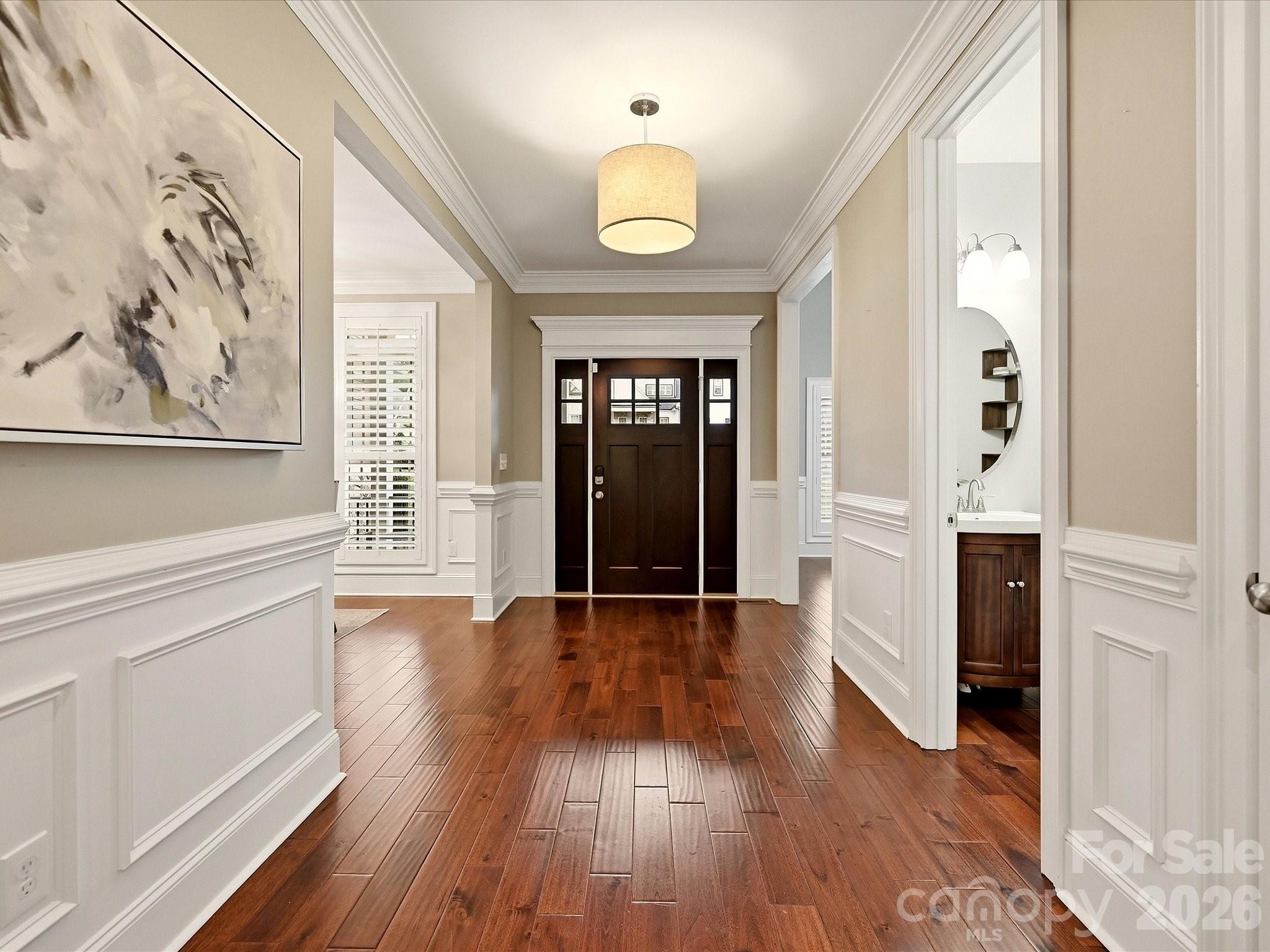 A spacious foyer welcomes you with rich flooring, elegant wainscoting, detailed crown molding, and a warm, refined entry into the home. - 3167 James Plantation Drive, Denver