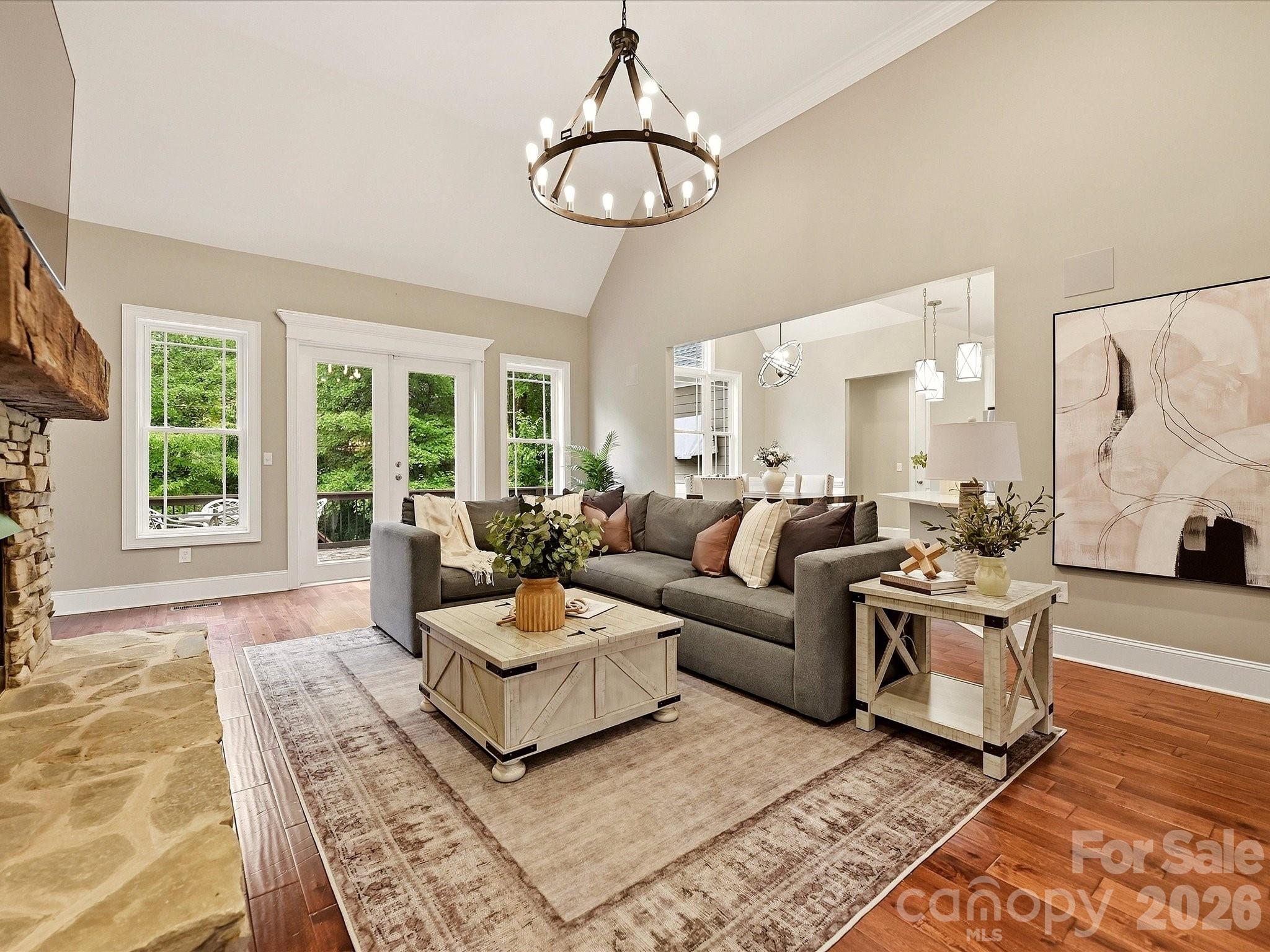 A spacious Great Room features soaring ceilings, rich floors, a dramatic stacked-stone fireplace, abundant natural light, and an open connection to the kitchen and dining areas. - 3167 James Plantation Drive, Denver