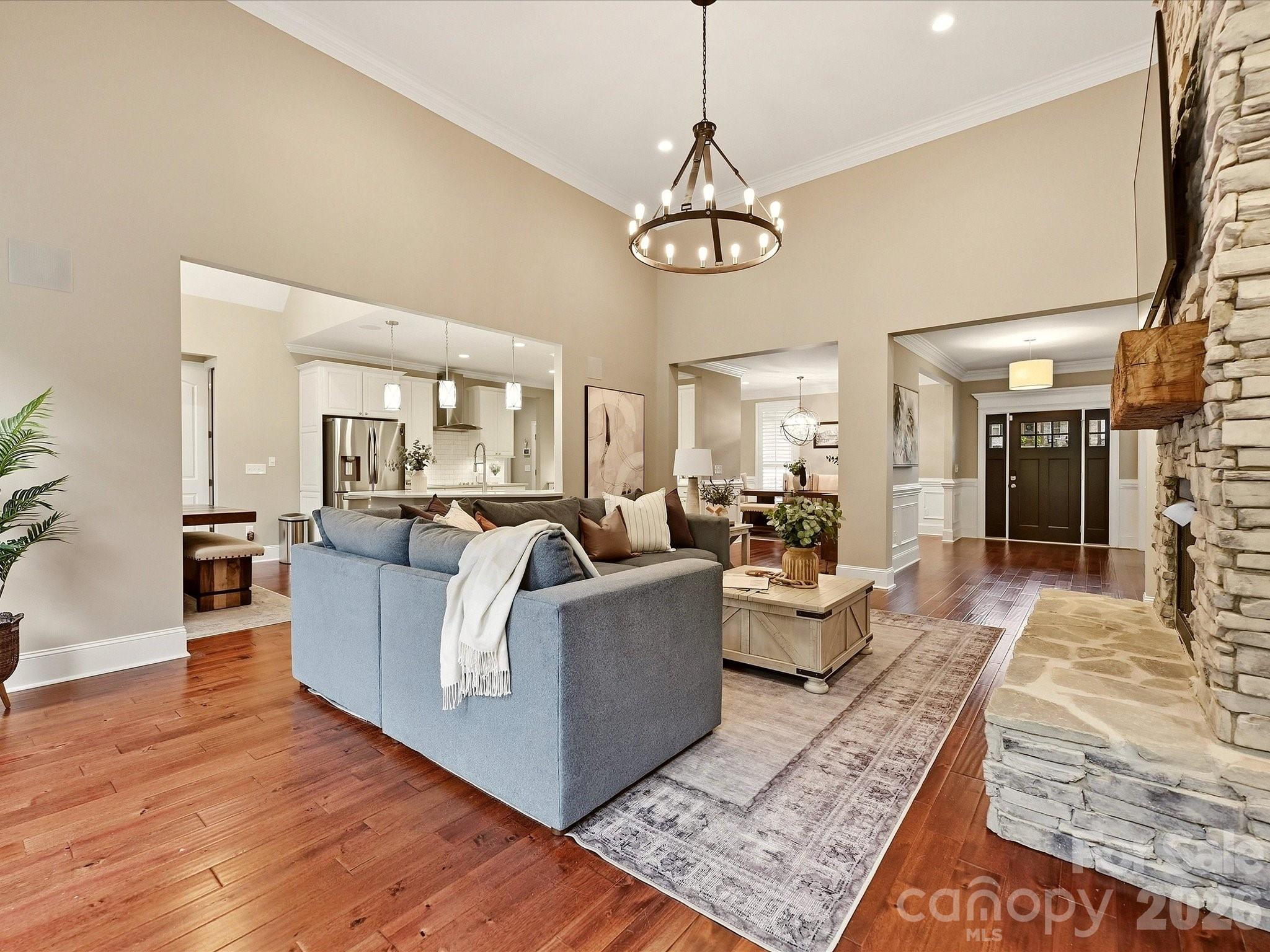 A spacious Great Room features soaring ceilings, beautiful flooring, a dramatic stacked-stone fireplace, abundant natural light, and an open connection to the kitchen and dining areas. - 3167 James Plantation Drive, Denver