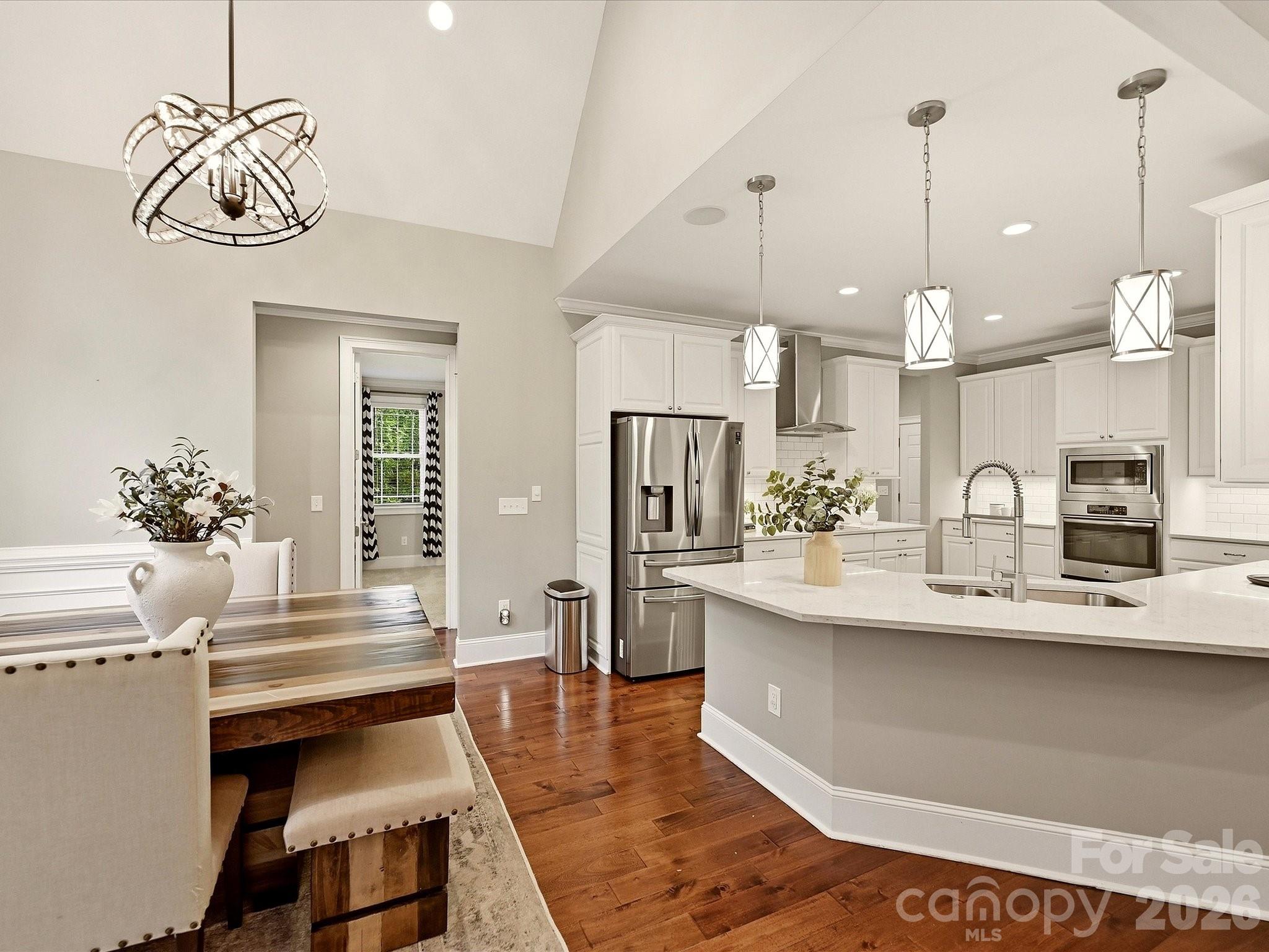 A beautifully updated kitchen features crisp white cabinetry, quartz countertops, stainless steel appliances, subway tile backsplash, stylish pendant lighting, and an expansive island with generous workspace and seating. - 3167 James Plantation Drive, Denver