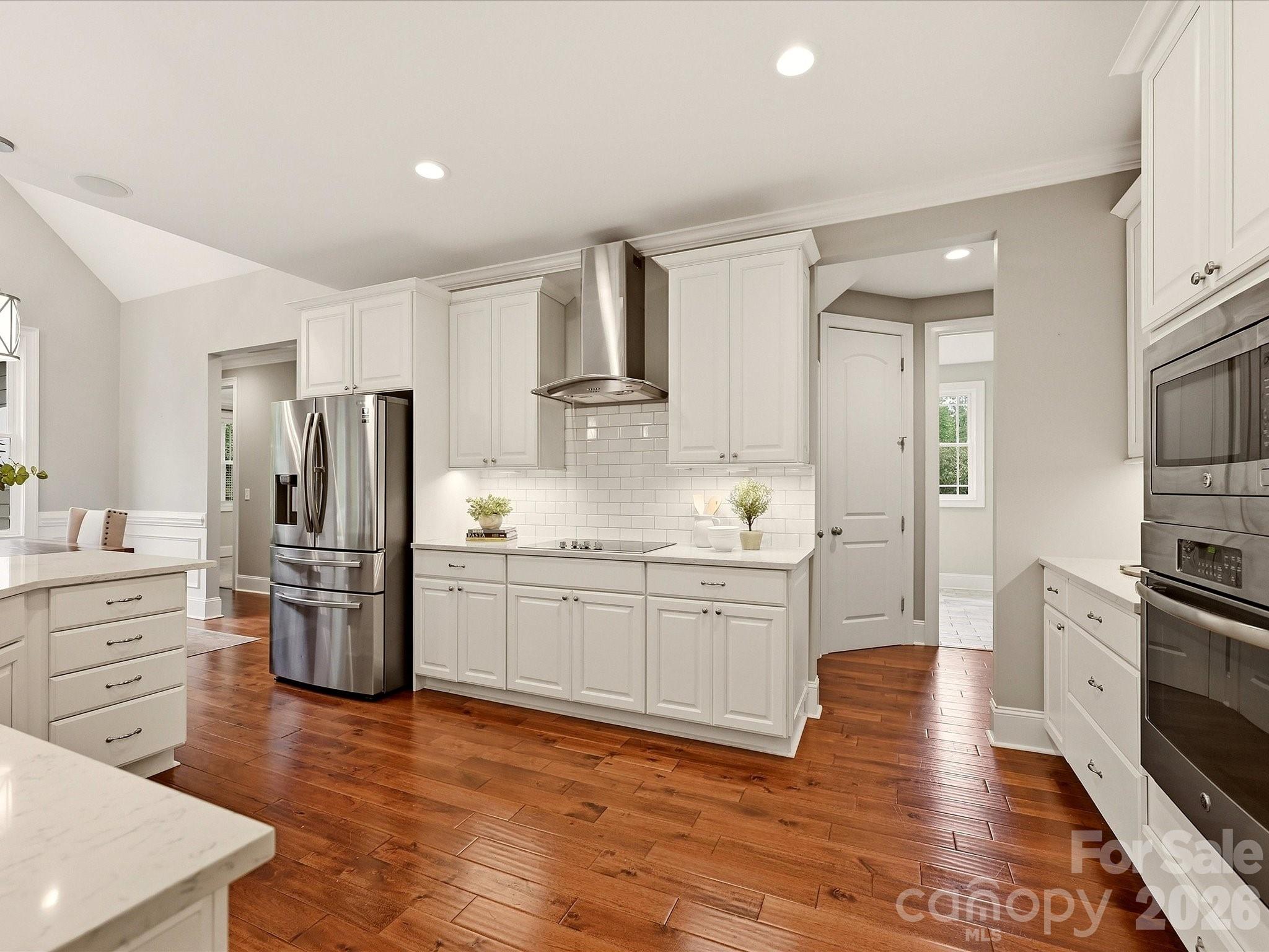 A beautifully updated kitchen features crisp white cabinetry, quartz countertops, stainless steel appliances, subway tile backsplash, stylish pendant lighting, and an expansive island with generous workspace and seating. - 3167 James Plantation Drive, Denver