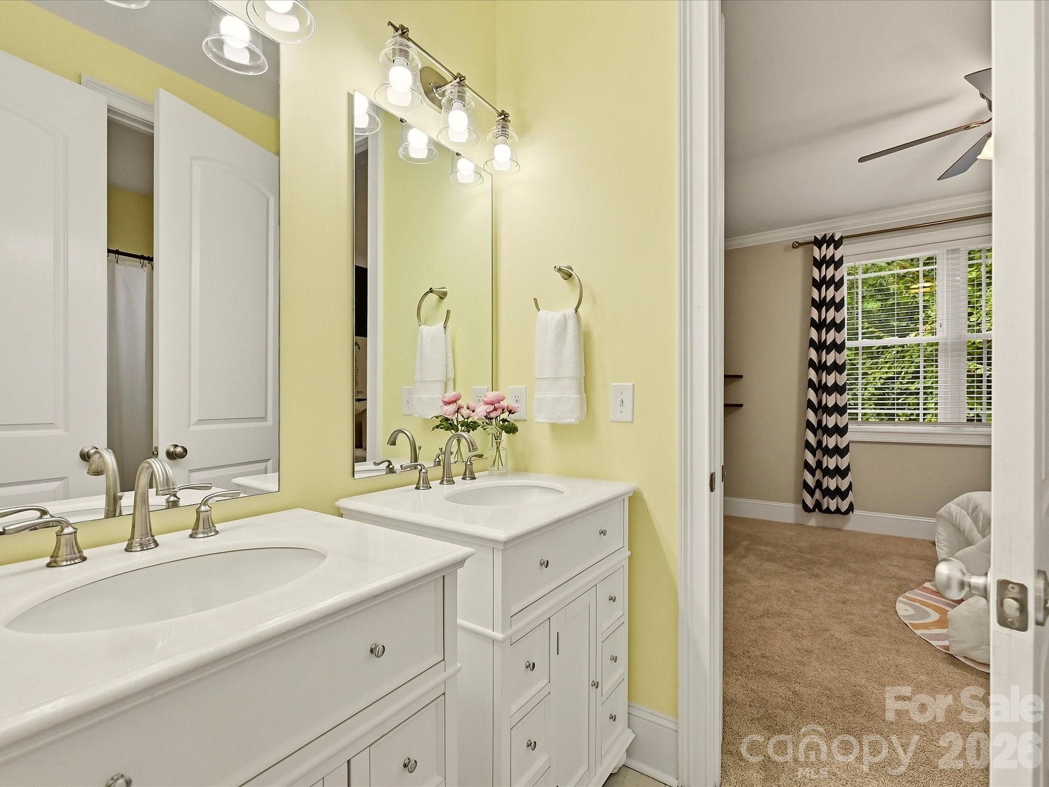 A convenient Jack-and-Jill bath features separate vanities, generous storage, bright lighting, and direct access between the adjoining bedrooms. - 3167 James Plantation Drive, Denver