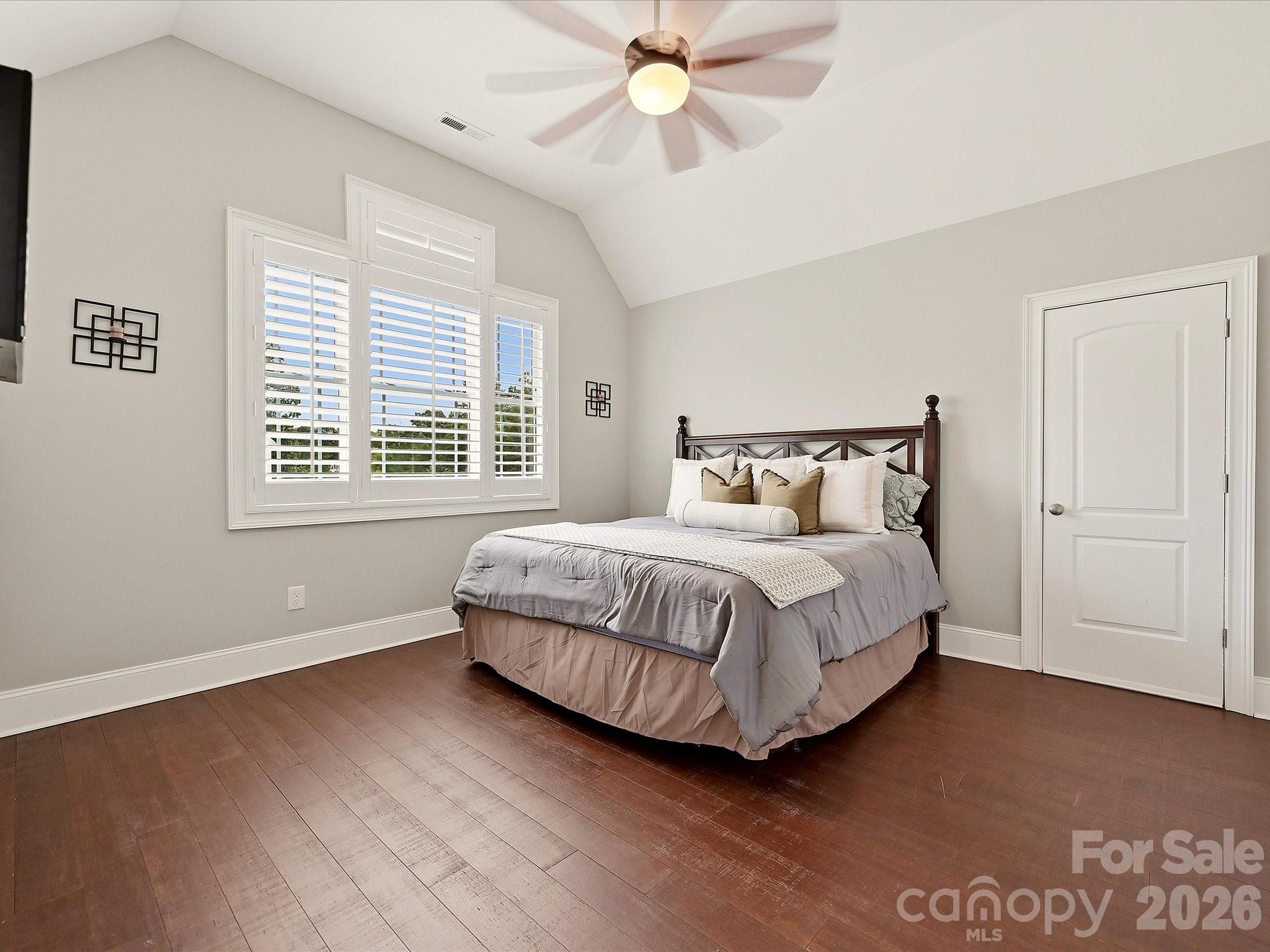 Bedroom 4 features vaulted ceilings, rich hardwood floors, plantation shutters, a ceiling fan, and generous space for comfortable everyday living. - 3167 James Plantation Drive, Denver