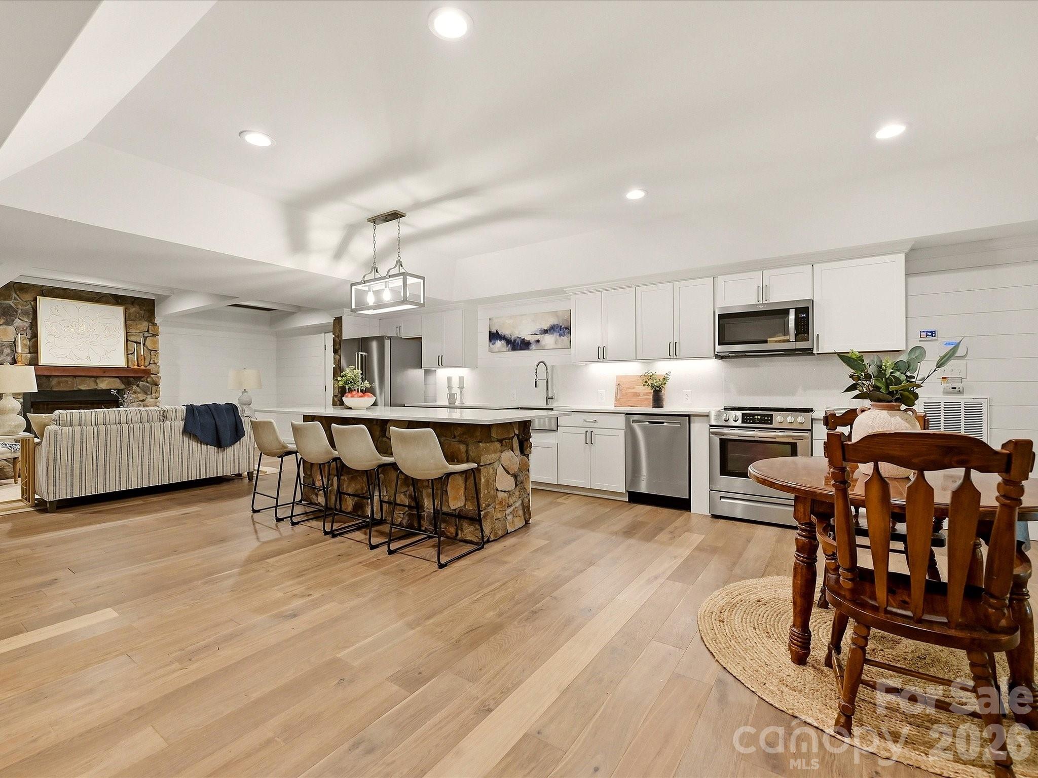A beautifully finished basement level offers expansive open-concept living with a full kitchen, spacious lounge area, stone accents, designer ceiling details, and flexible space for entertaining or extended-stay guests. - 3167 James Plantation Drive, Denver