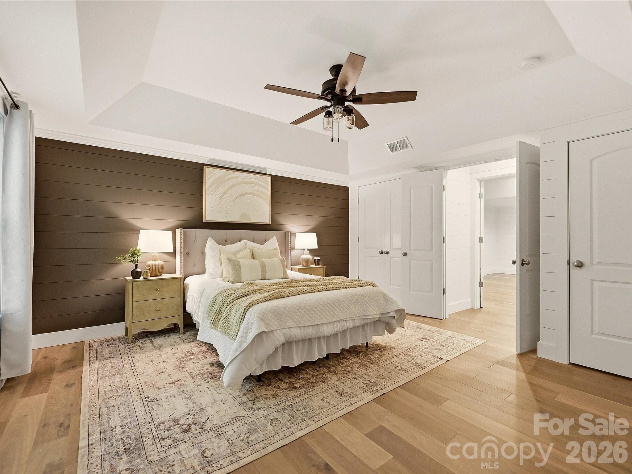 Bedroom 5 on basement level offers generous space with light wood flooring, a vaulted ceiling, ceiling fan, and a stylish shiplap accent wall for added character. - 3167 James Plantation Drive, Denver
