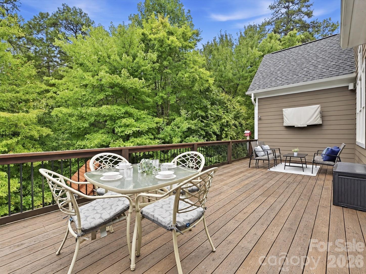 An expansive back deck offers multiple outdoor dining and lounge areas with a natural wood finish, peaceful wooded views, and plenty of space for relaxing or entertaining. - 3167 James Plantation Drive, Denver