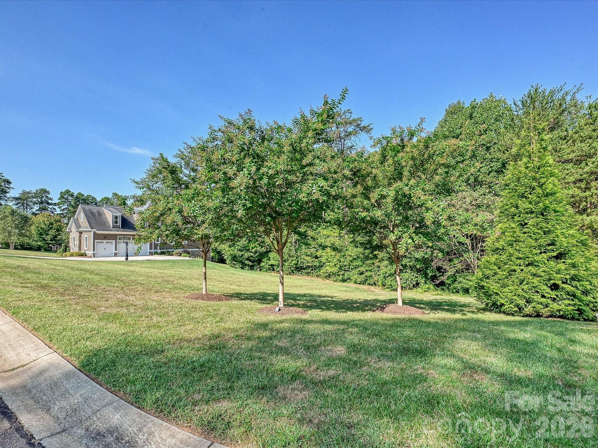 Beautifully maintained landscaping features an expansive lawn, mature trees, and a peaceful wooded backdrop that enhances the home’s privacy and curb appeal. - 3167 James Plantation Drive, Denver