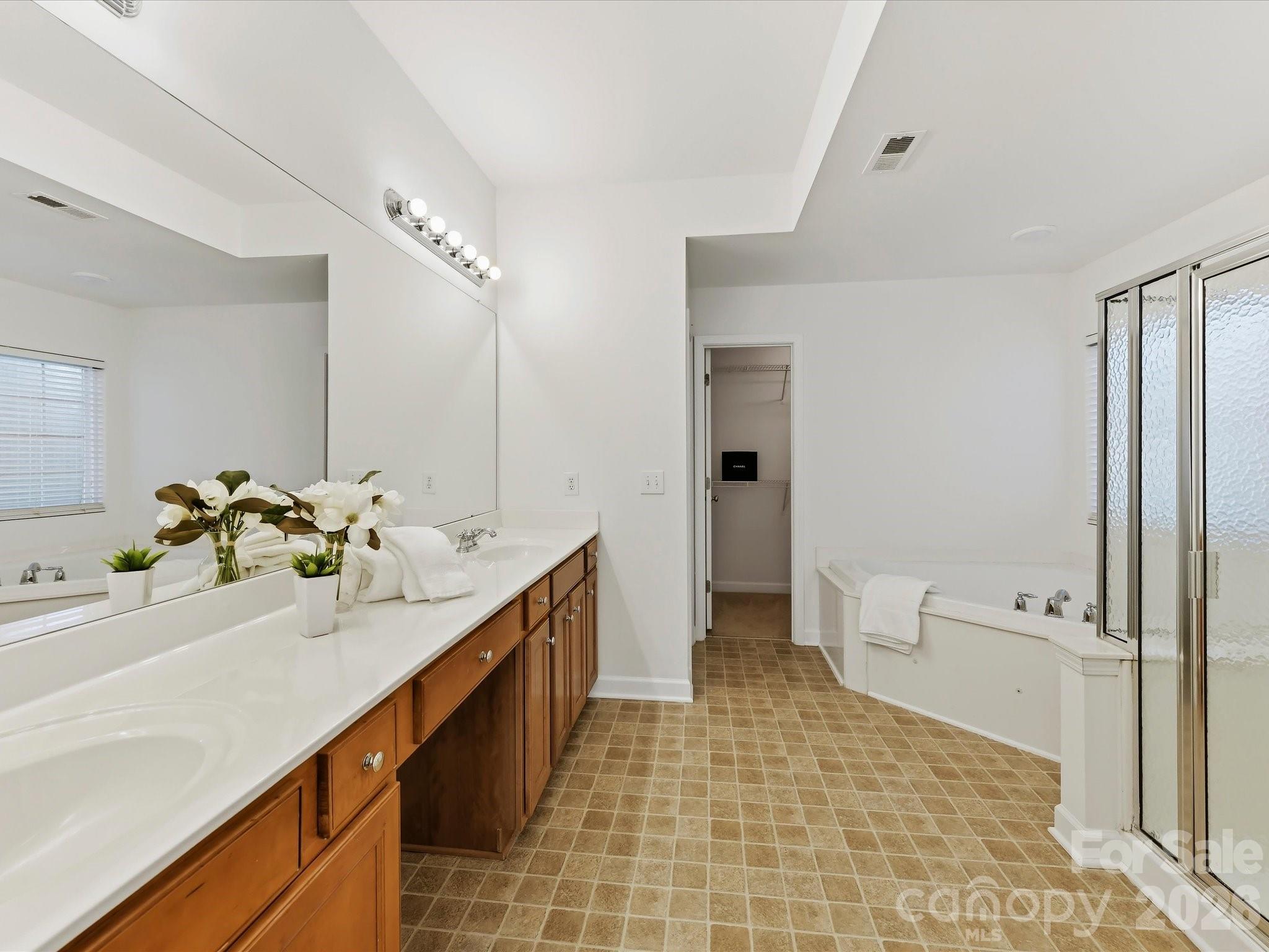 A spacious double vanity with makeup table is featured in the Primary bath. - 8128 Madrigal Court, Waxhaw