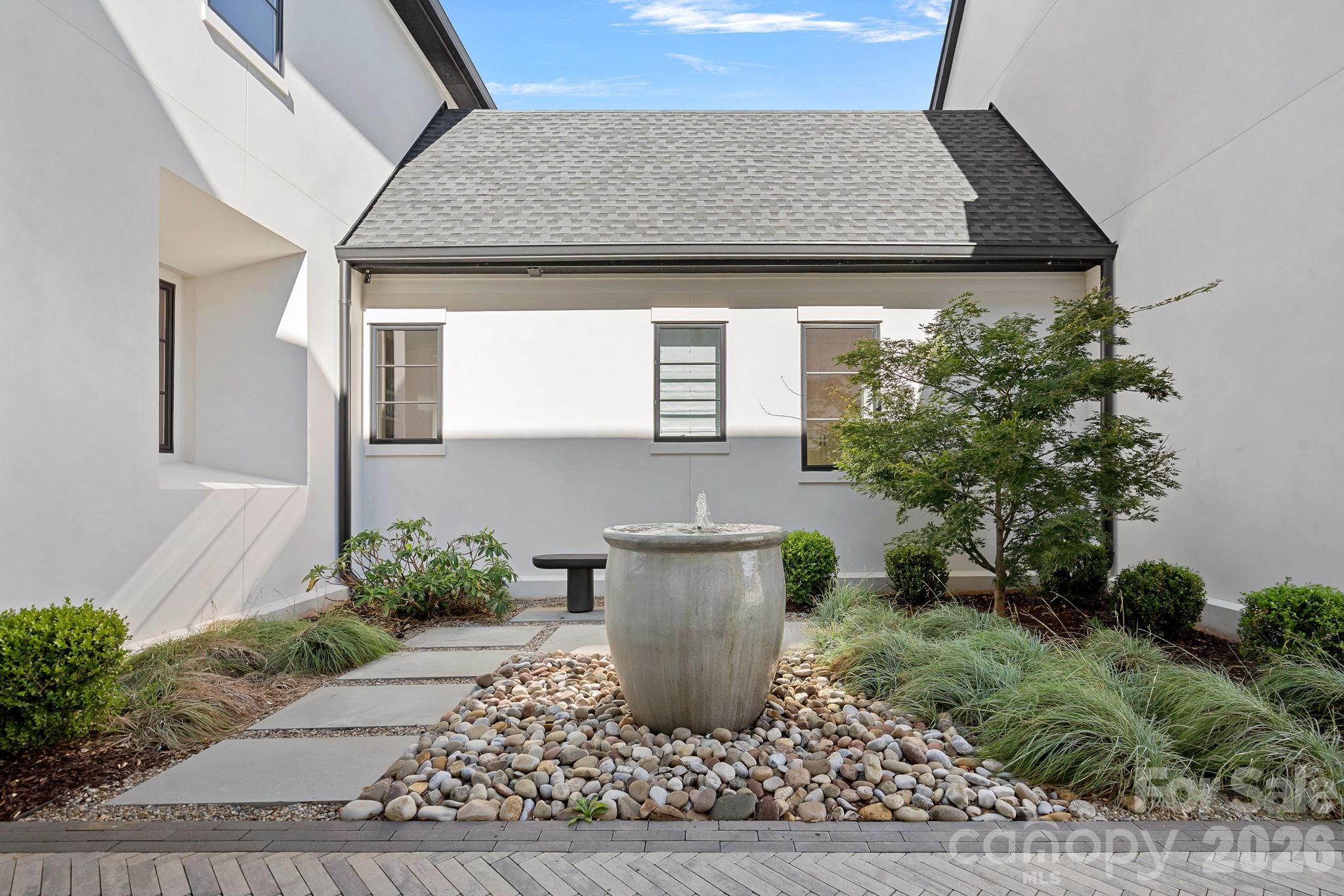 Tranquil garden courtyard with sculptural fountain and thoughtfully curated landscaping. - 17811 Largo Place, Cornelius