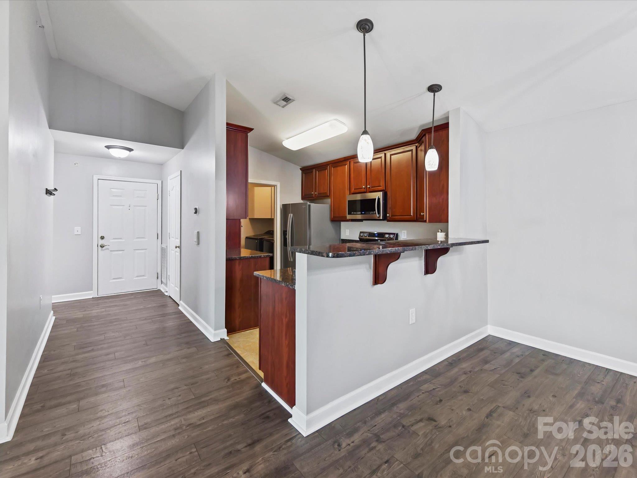 Well-appointed kitchen featuring rich wood cabinetry, granite countertops, stainless steel appliances, generous storage, and a convenient breakfast bar opening to the main living areas. - 9031 Mcdowell Creek Court, Cornelius