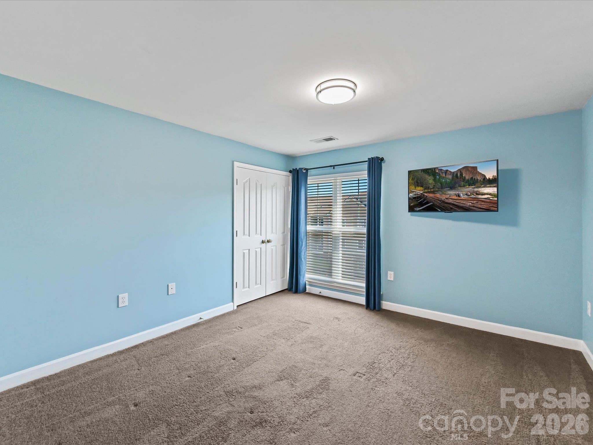 Spacious second bedroom featuring plush carpeting, ample natural light, generous closet space, and flexible room for guests, a home office, or additional living space. - 9031 Mcdowell Creek Court, Cornelius