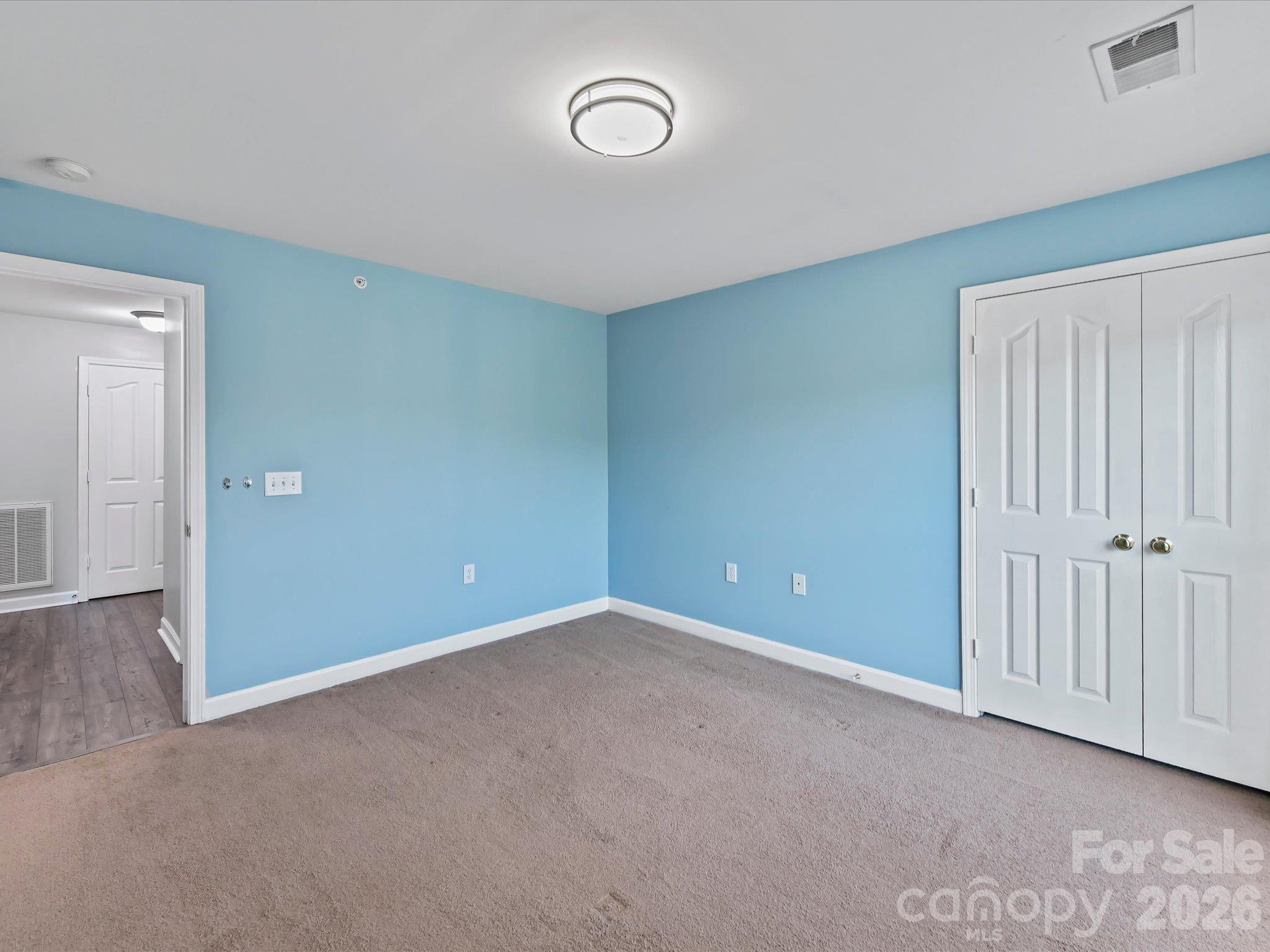 Spacious second bedroom featuring plush carpeting, ample natural light, generous closet space, and flexible room for guests, a home office, or additional living space. - 9031 Mcdowell Creek Court, Cornelius