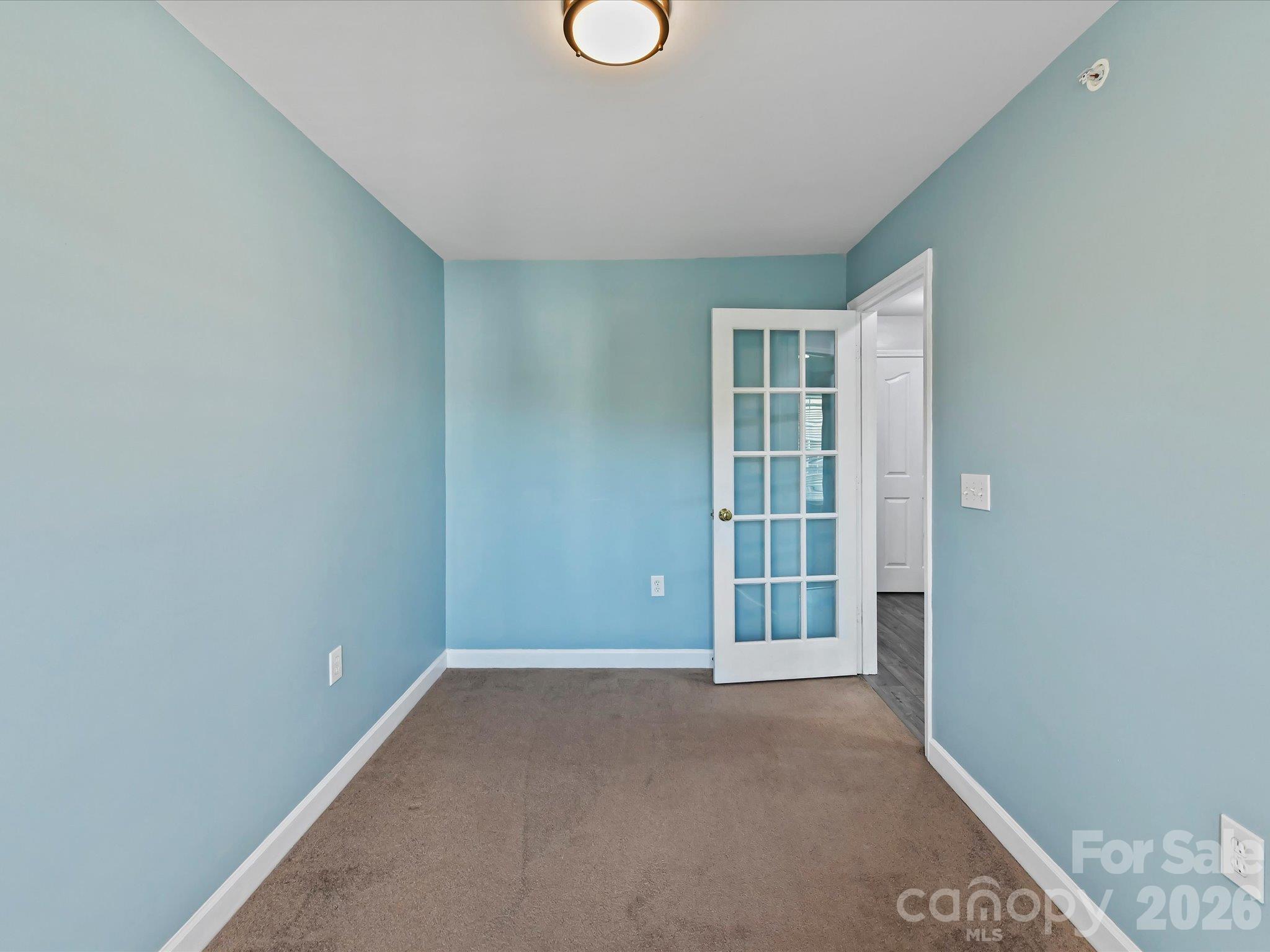 Versatile flex room featuring plush carpeting, abundant natural light, and French-door entry—ideal for a home office, guest space, or hobby room. - 9031 Mcdowell Creek Court, Cornelius