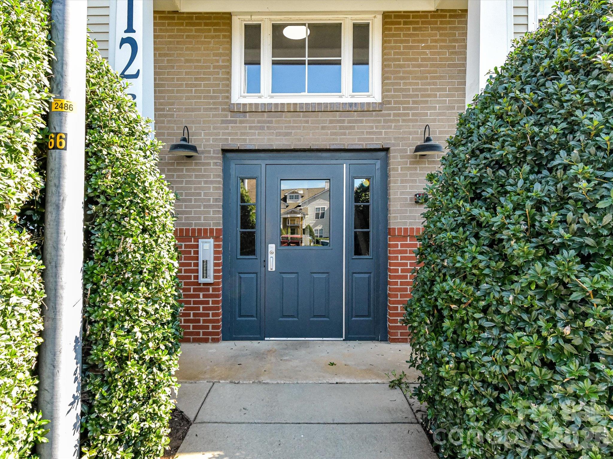 Convenient rear building entrance featuring a covered entry, secure access, and well-maintained landscaping for easy everyday access to the condo. - 9031 Mcdowell Creek Court, Cornelius