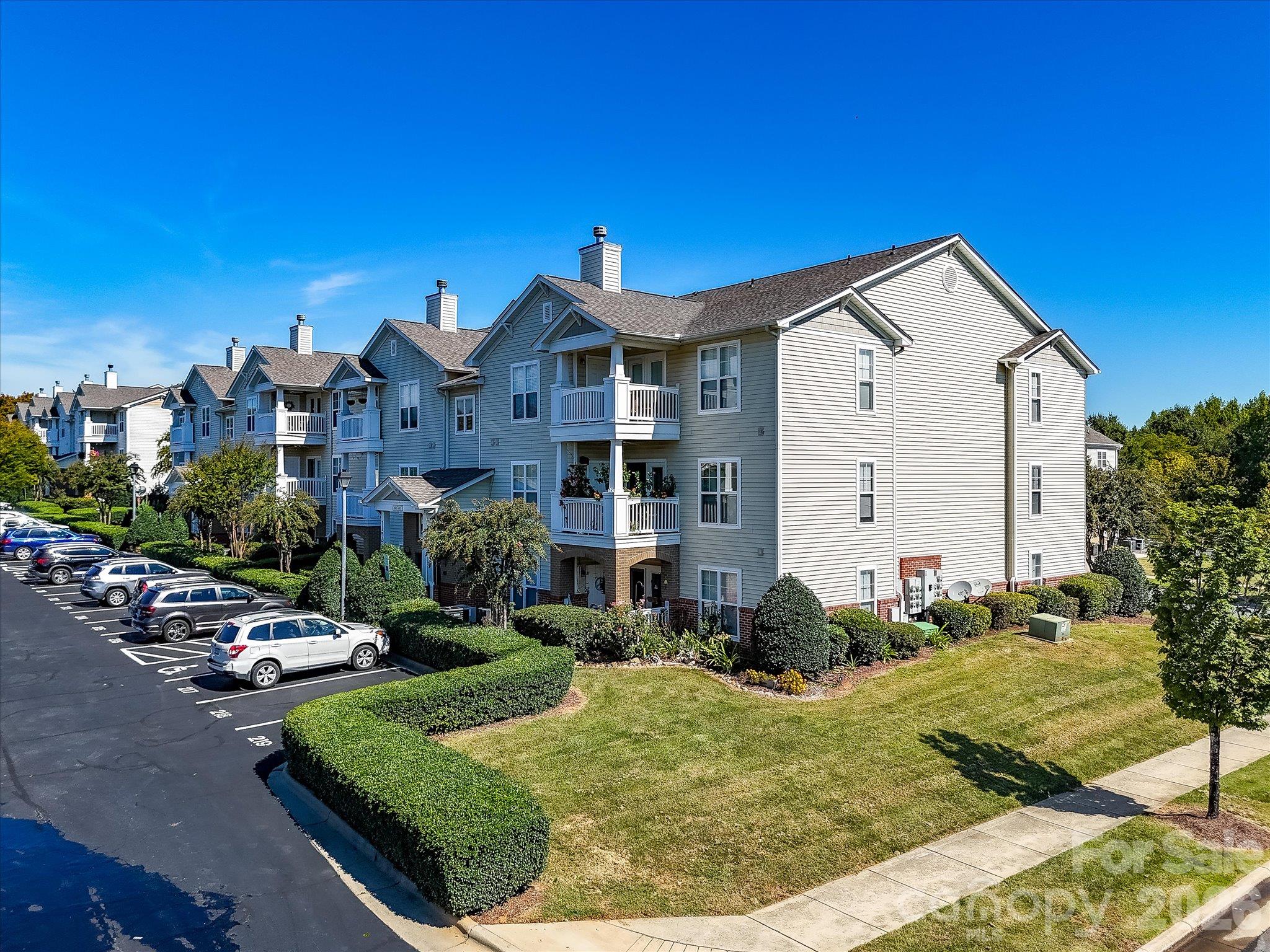 Alternate aerial view showcases the well-maintained condo building with covered balconies, landscaped grounds, convenient parking, and attractive community surroundings. - 9031 Mcdowell Creek Court, Cornelius