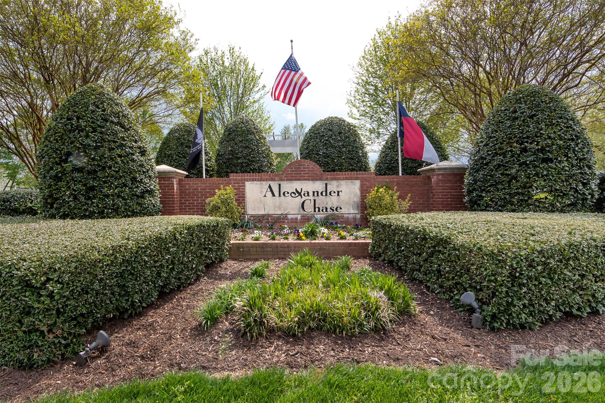 Welcoming entrance to the Alexander Chase community featuring attractive brick signage, mature landscaping, and beautifully maintained grounds. - 9031 Mcdowell Creek Court, Cornelius