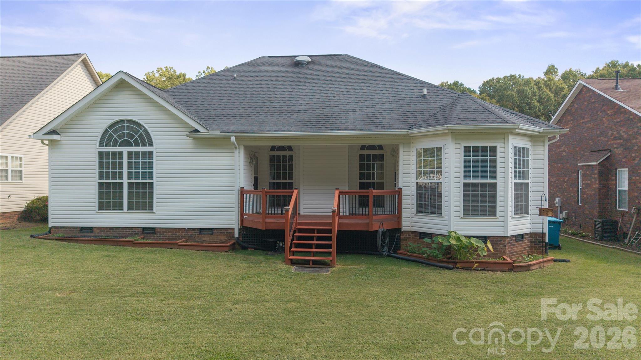 Spacious, grassy backyard featuring a wooden covered deck, low-maintenance vinyl siding, large sun-filling windows, and bay window nook. - 1011 Overhill Road, Salisbury