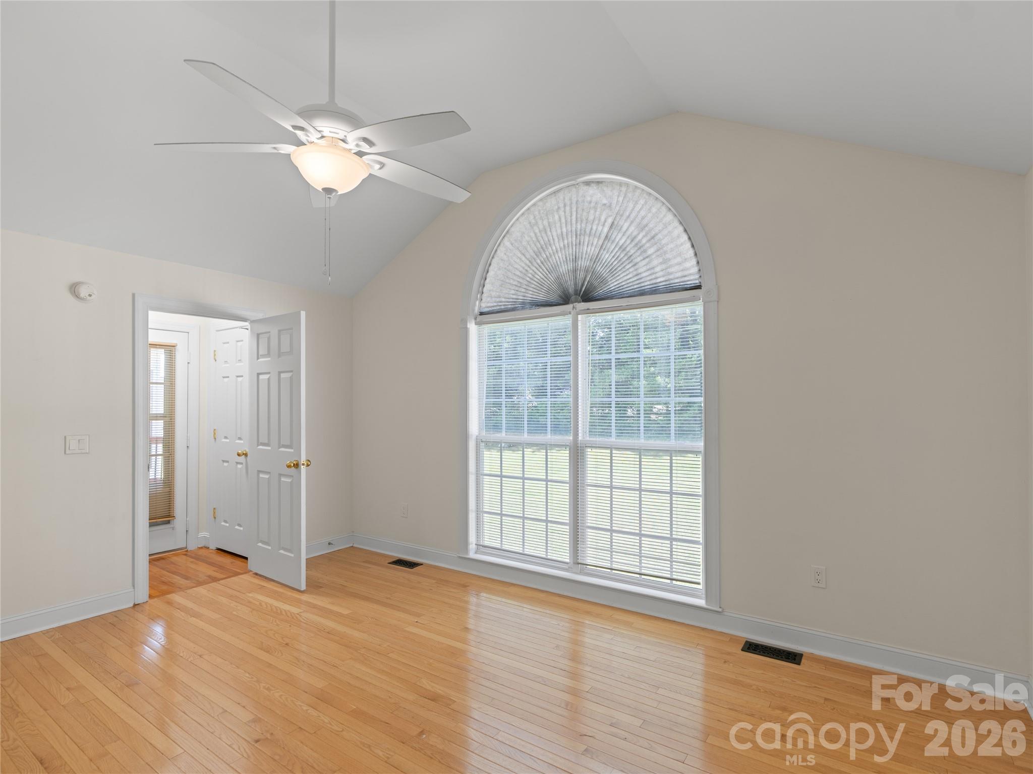 In the primary suite, gorgeous arched windows let in tons of natural light, vaulted ceilings and newer light fixture/ceiling fan. The door to the left walks out onto the covered back.deck. - 1011 Overhill Road, Salisbury
