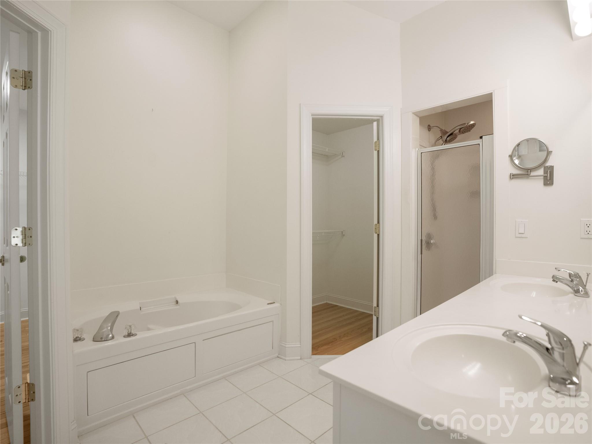 Primary ensuite bathroom featuring a deep soaking jet-garden tub, dual-sink vanity, separate walk-in shower, tile flooring, and direct access to a dual walk-in closets - 1011 Overhill Road, Salisbury