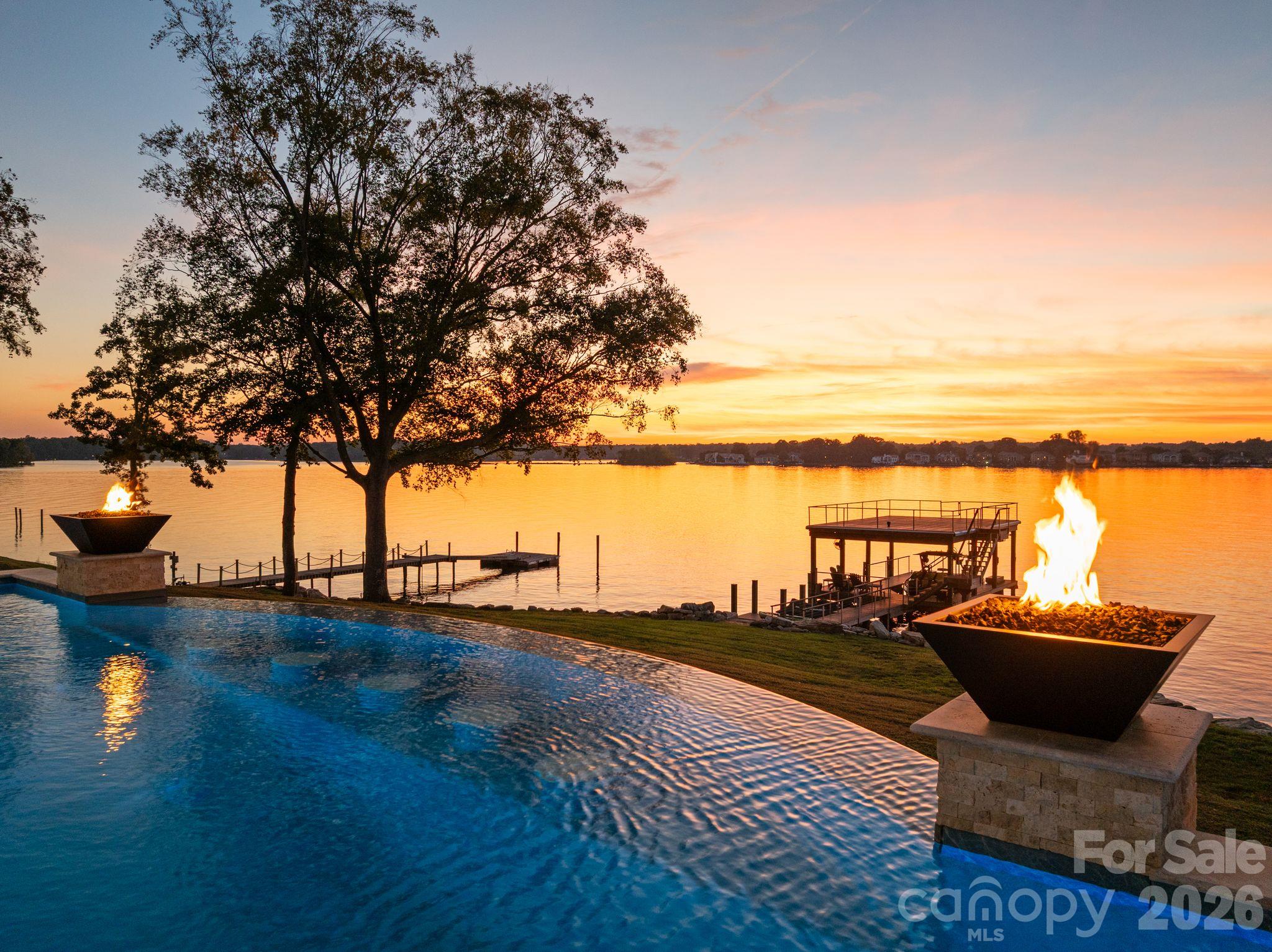 Infinity-edge pool with fire bowls framed by a stunning Lake Norman sunset. - 112 Birdsong Lane, Mooresville