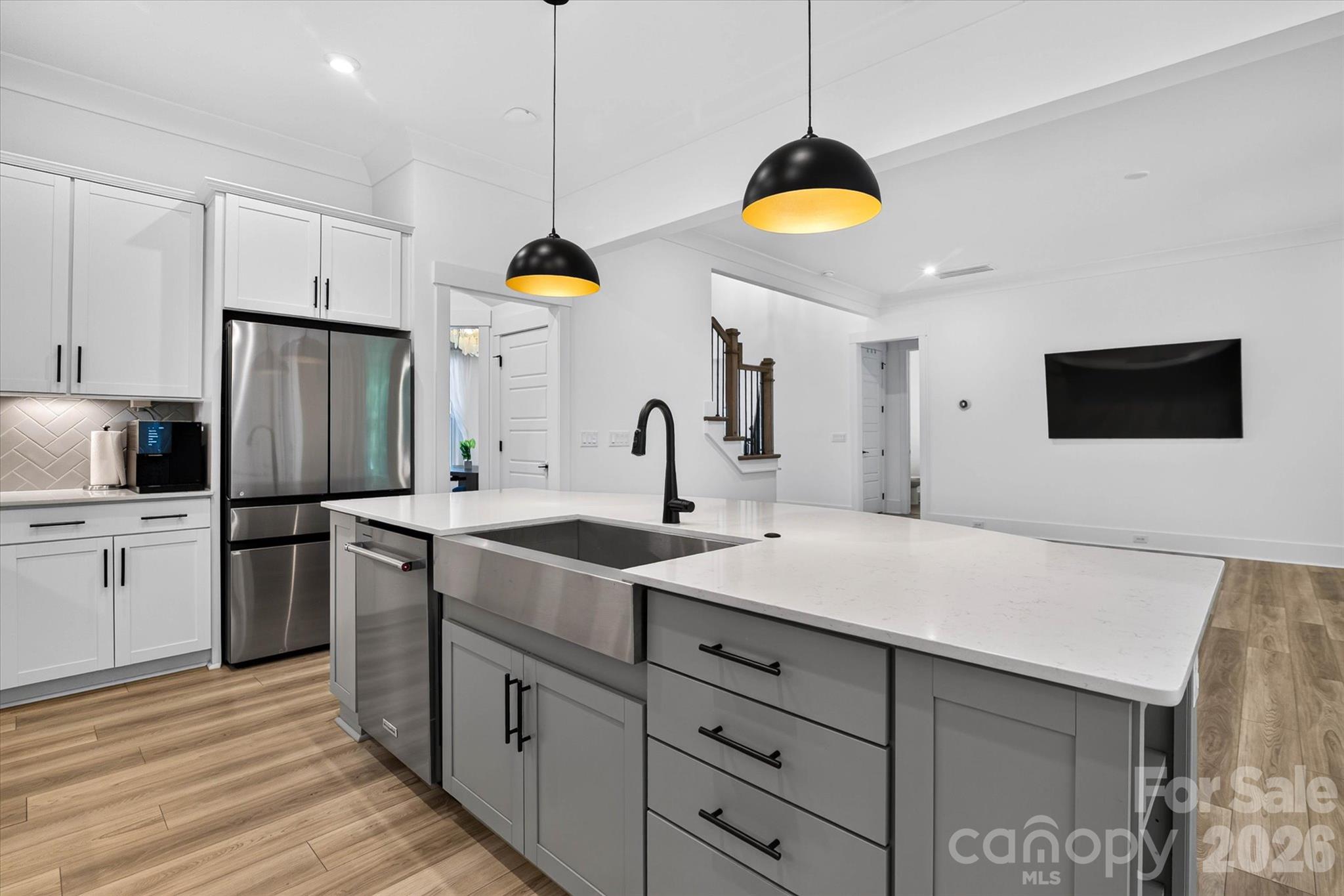 The island where coffee gets poured, and dinner conversations start. Every detail, from the farmhouse sink to the gold-lit pendants, was chosen with intention. - 1216 Glade Arch Lane, Huntersville