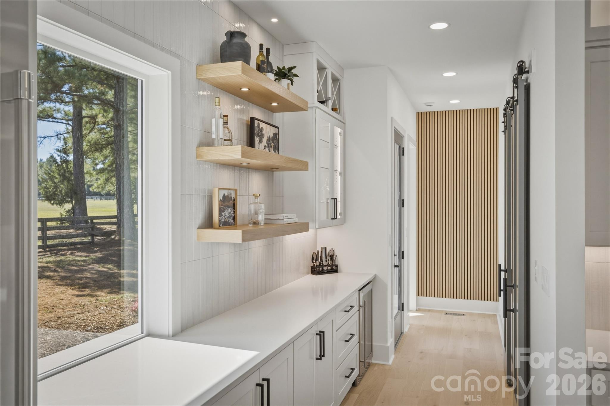 The bar area of this amazing kitchen is highlighted by the floating LED lighted shelves, glass fronted cabinets, and the undercounter beverage refrigerator, and another large window. - 2303 Paddock Circle, Morganton