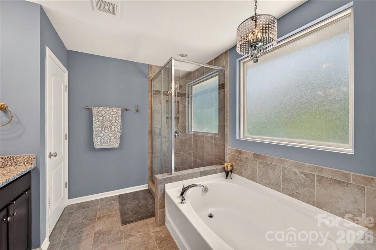 Primary bath with soaking tub and tiled shower with glass doors - 3093 Hartson Pointe Drive, Fort Mill