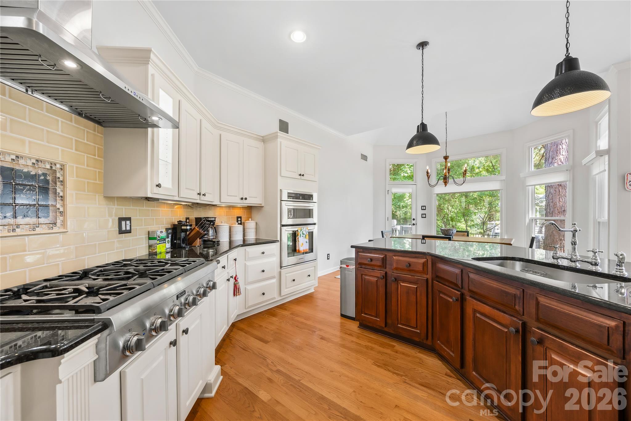 kitchen features premium updated stainless steel appliances, granite countertops, a Thermador 6-burner gas range, backlit cabinetry, and a massive center island. - 15728 Delancey Lane, Huntersville